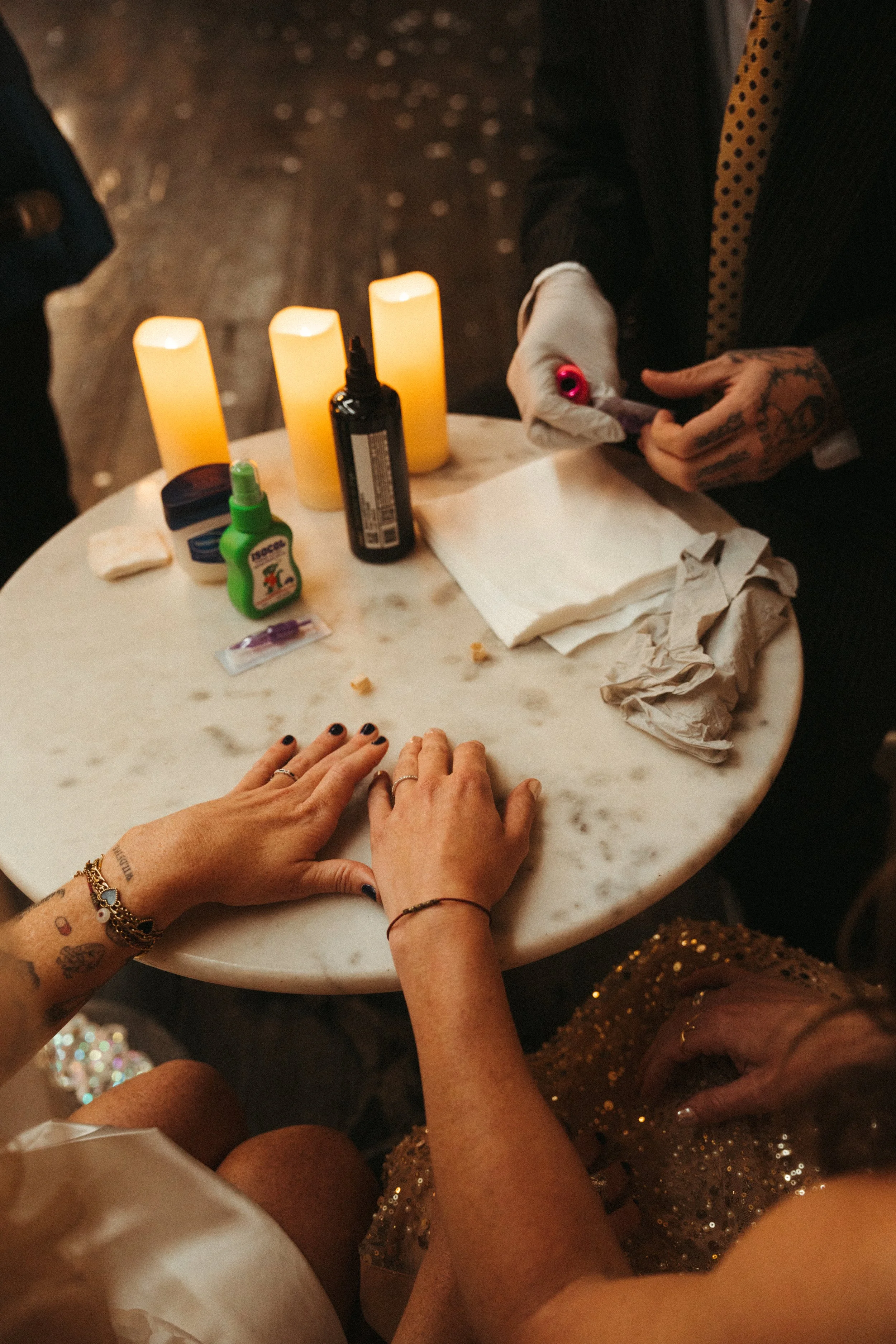 Outdoor night wedding reception with elegantly decorated table, white tablecloth, chairs, floral centerpieces, illuminated by string lights.