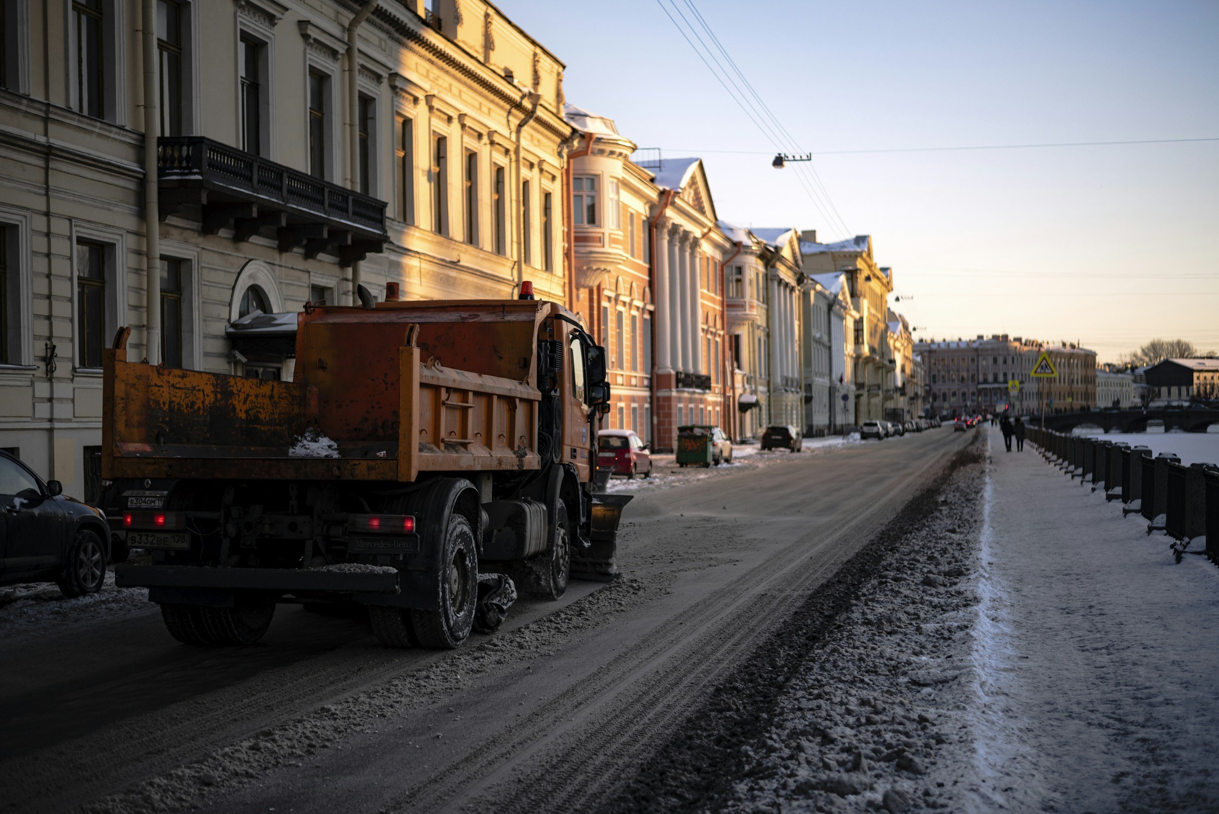 Dump truck driving beside historic buildings in an urban setting.