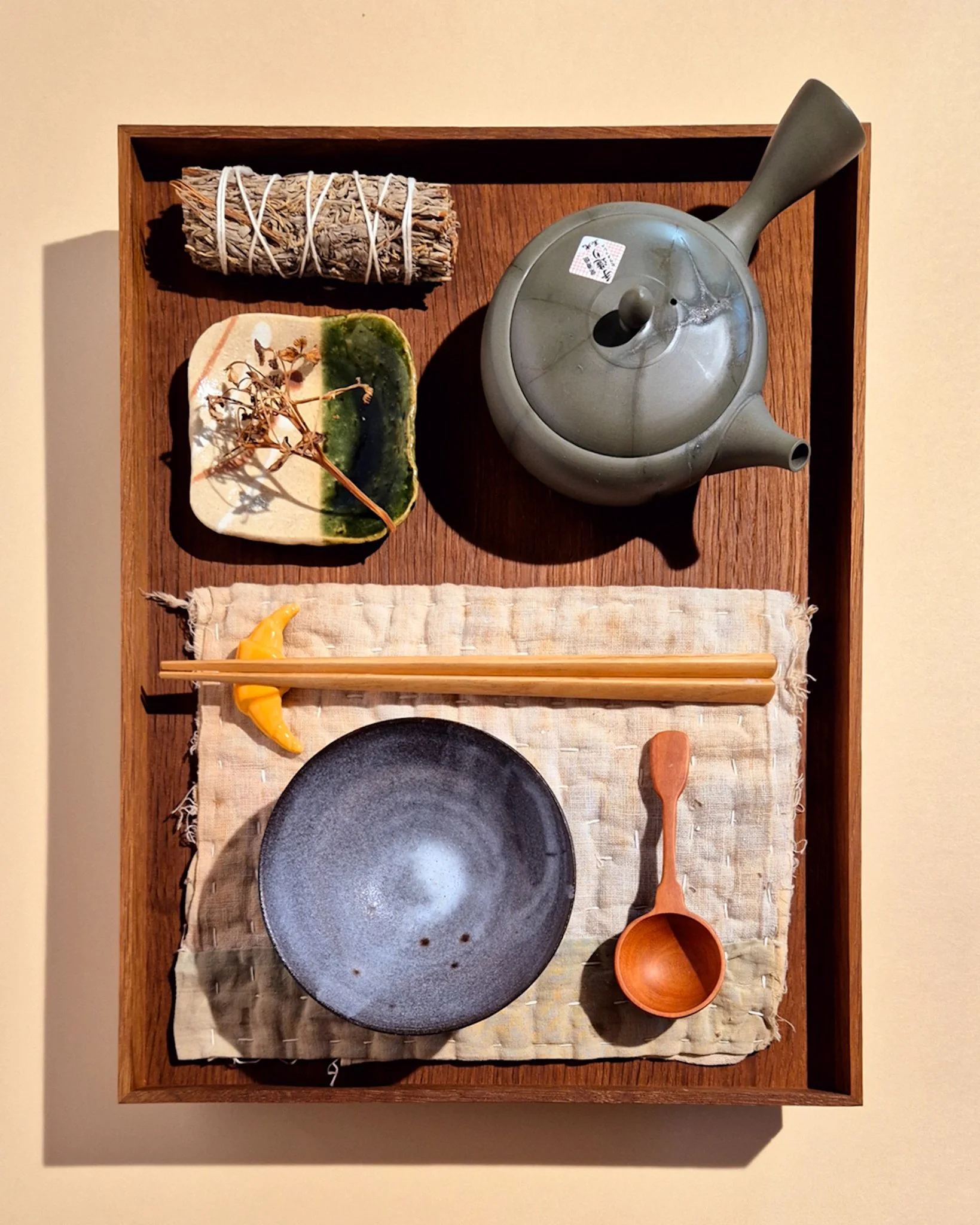 Japanese-inspired food styling with ceramics, textiles and small dishes arranged on a dark woven cloth.