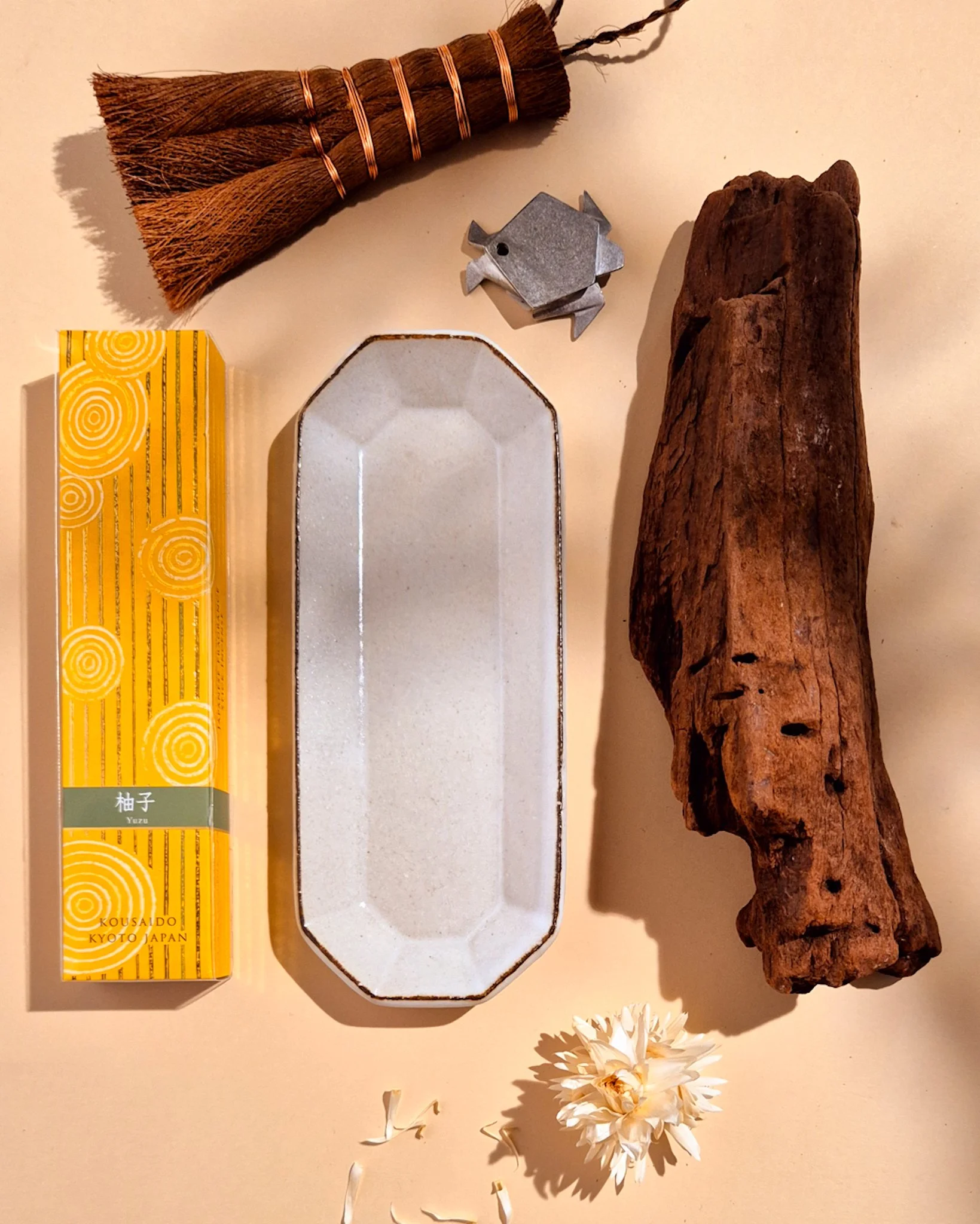 White Japanese teapot and cup styled with bamboo steamer and small decorative objects on a beige background.