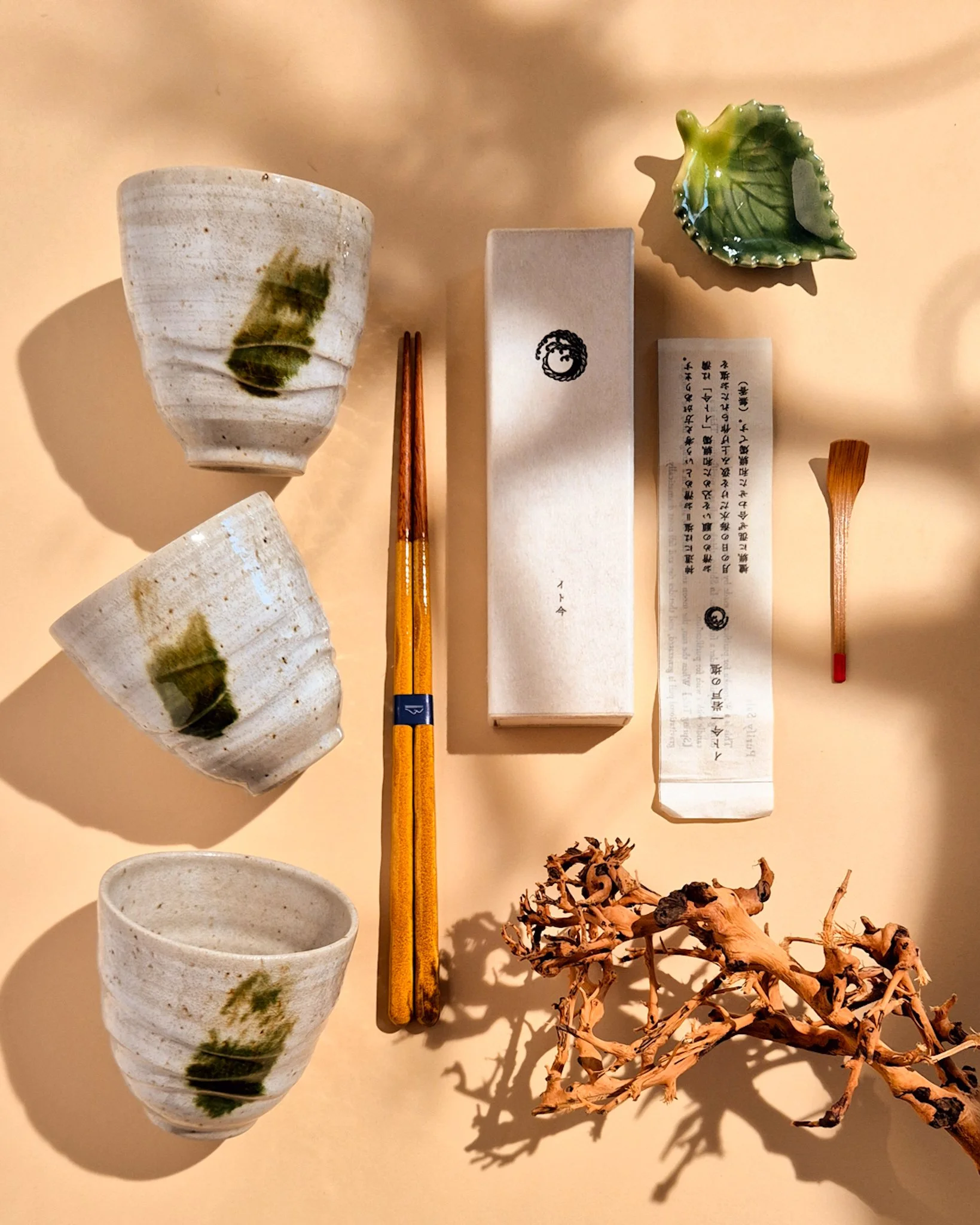 Stacked handmade stoneware cups or vases in dark ceramic tones on a warm neutral background.