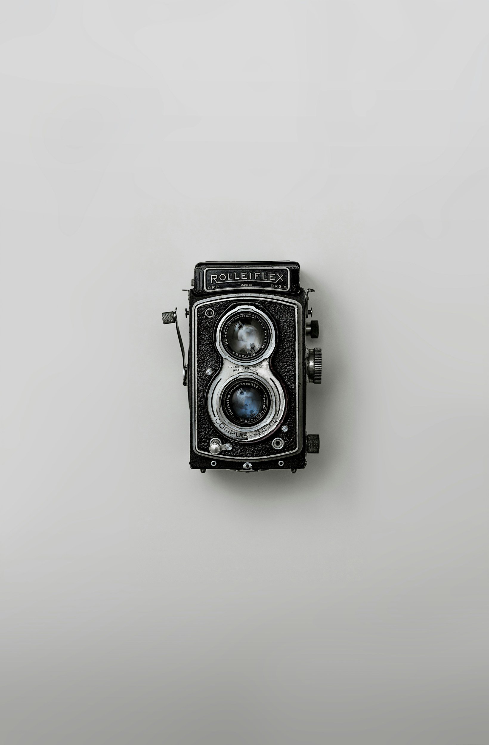 A vintage Rolleiflex twin-lens reflex camera on a white background.