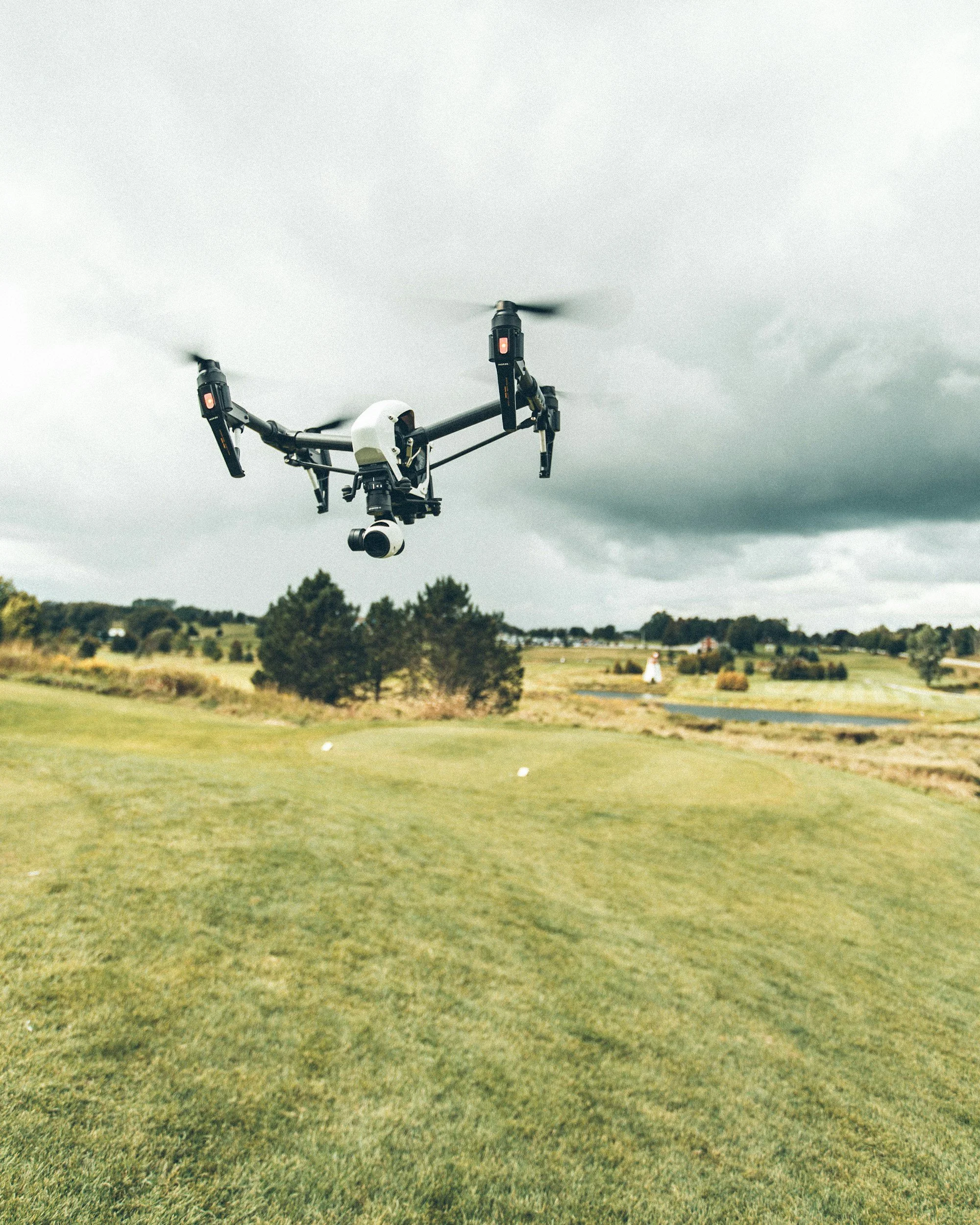 A drone flying over a golf course on a cloudy day.