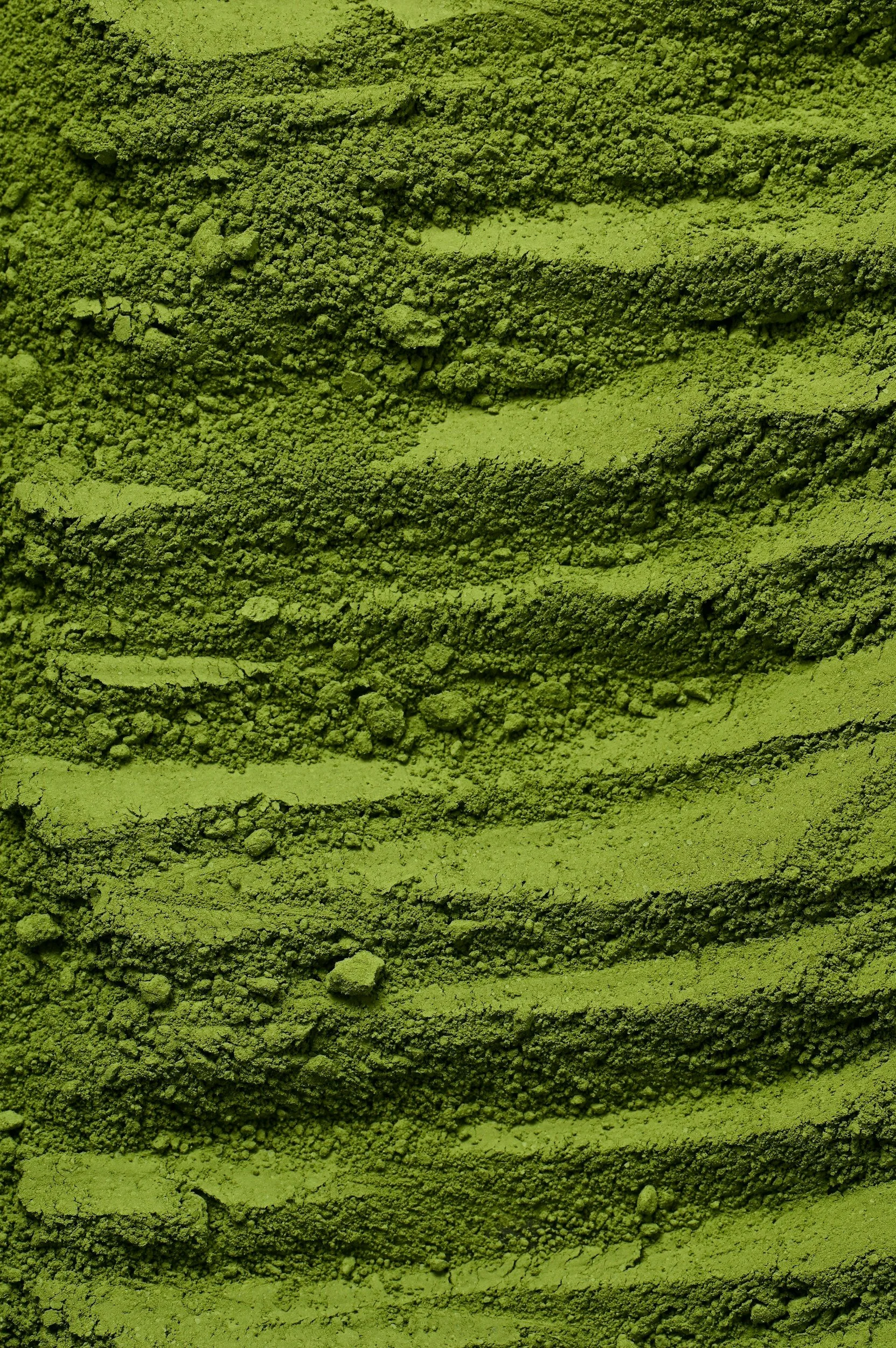 Close-up of green matcha powder layered in a rounded mold with textured, wavy pattern.