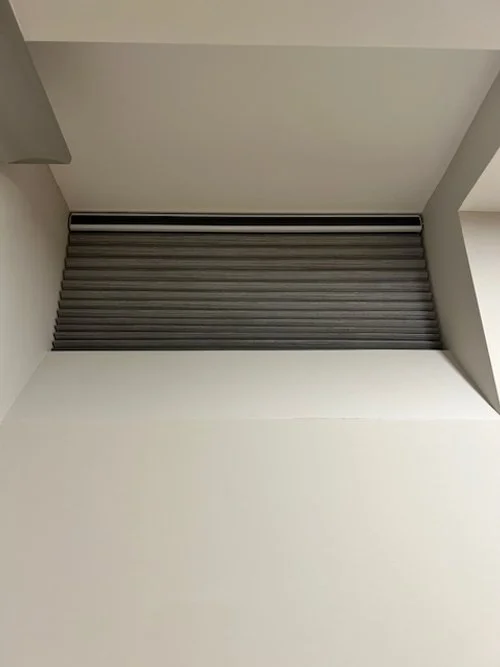 Recessed ceiling with a black and gray striped roller shade.