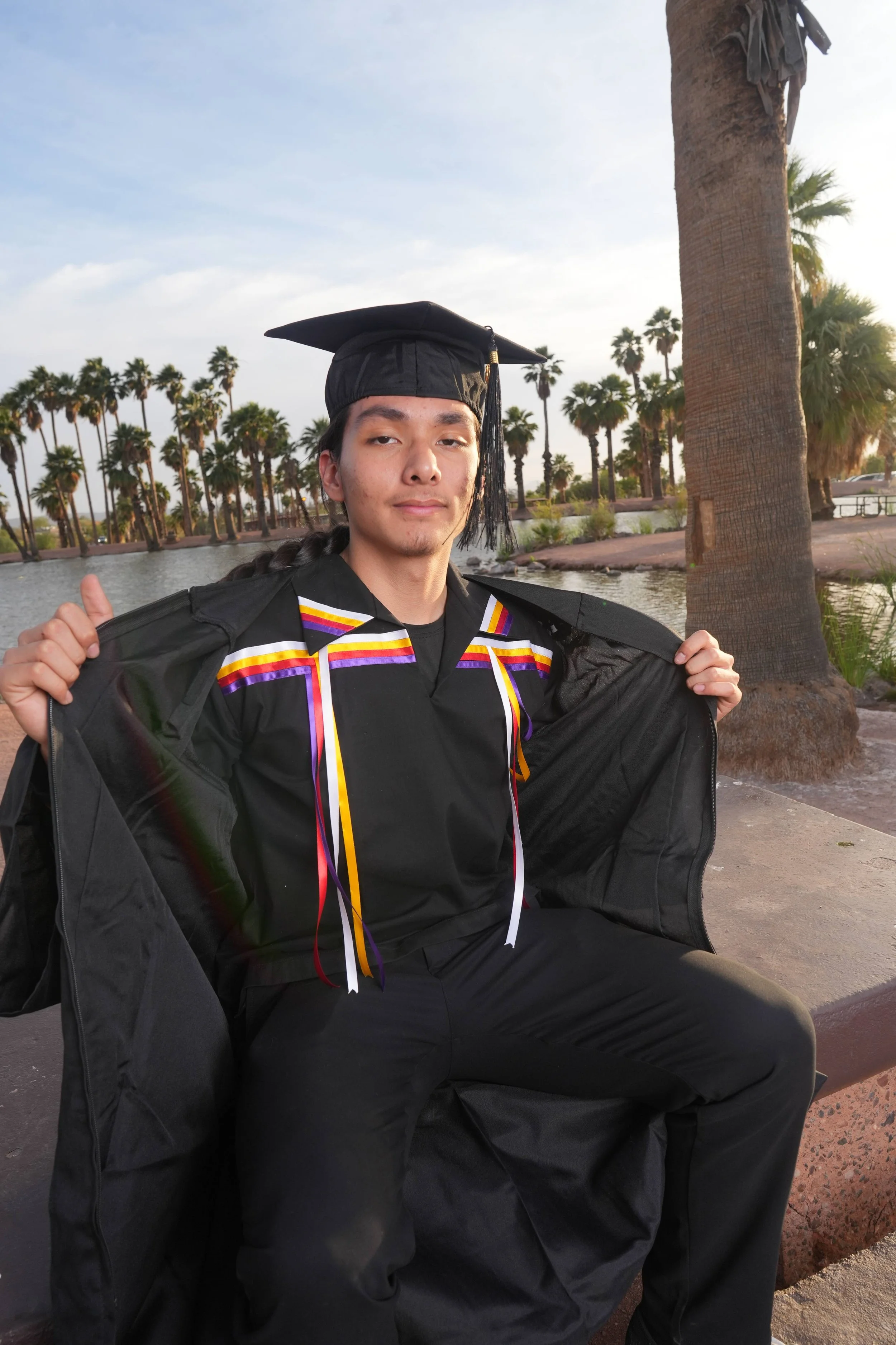 Male Arizona State Graduate climbing a horse