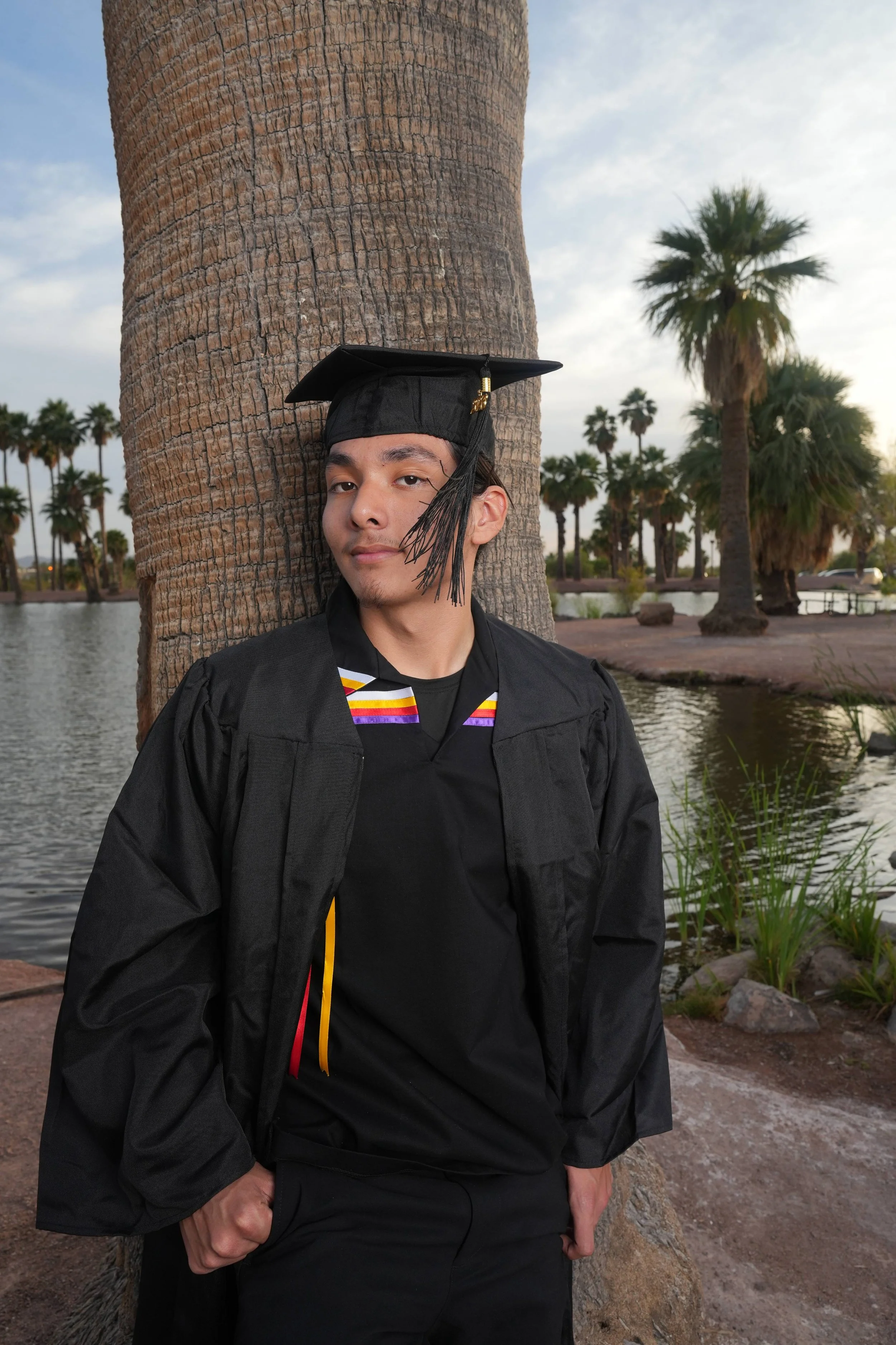 Arizona state graduate; Man in suit adjusting jacket on Phoenix, Arizona rooftop with sunset background.