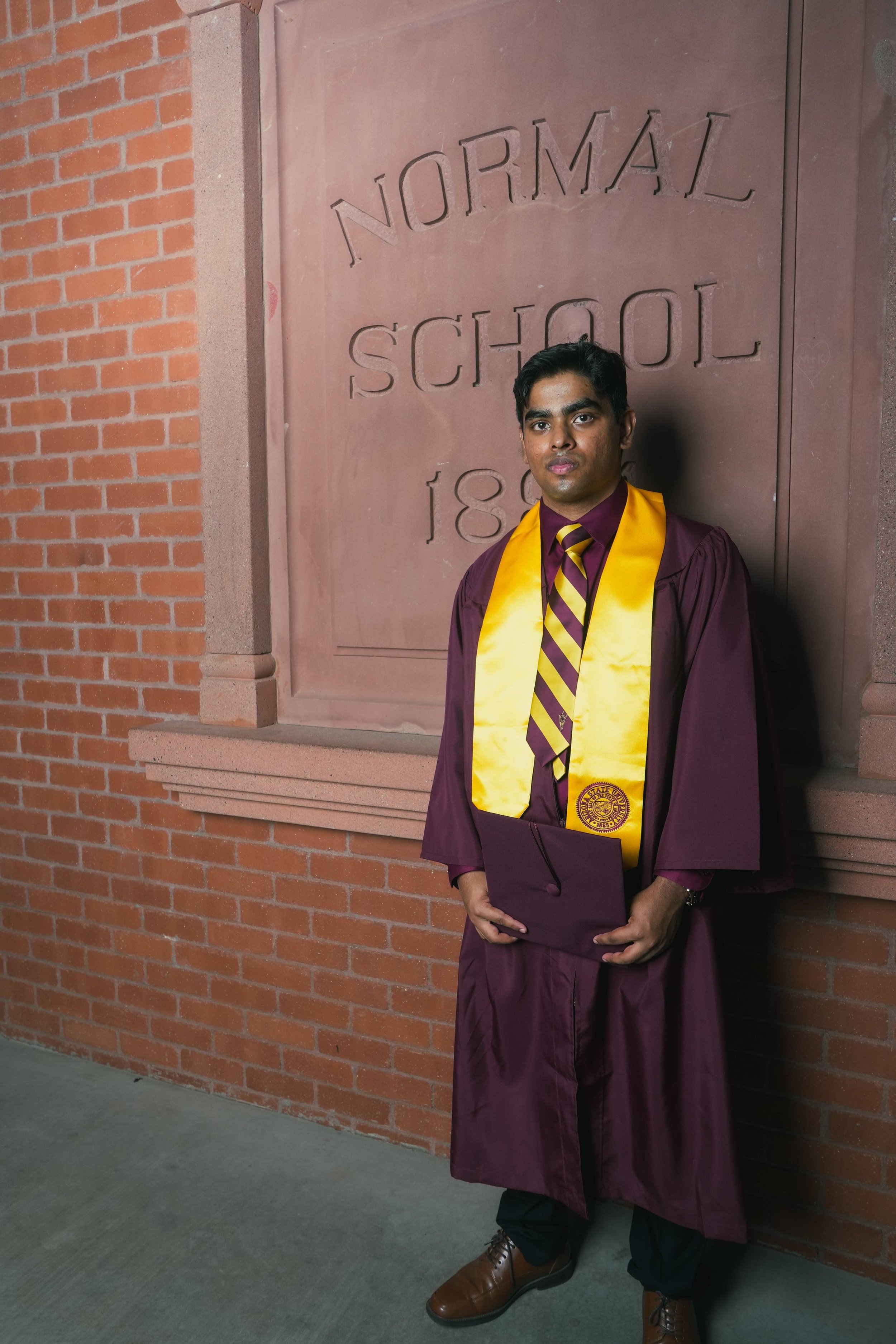 Male Arizona State Graduate climbing a horse
