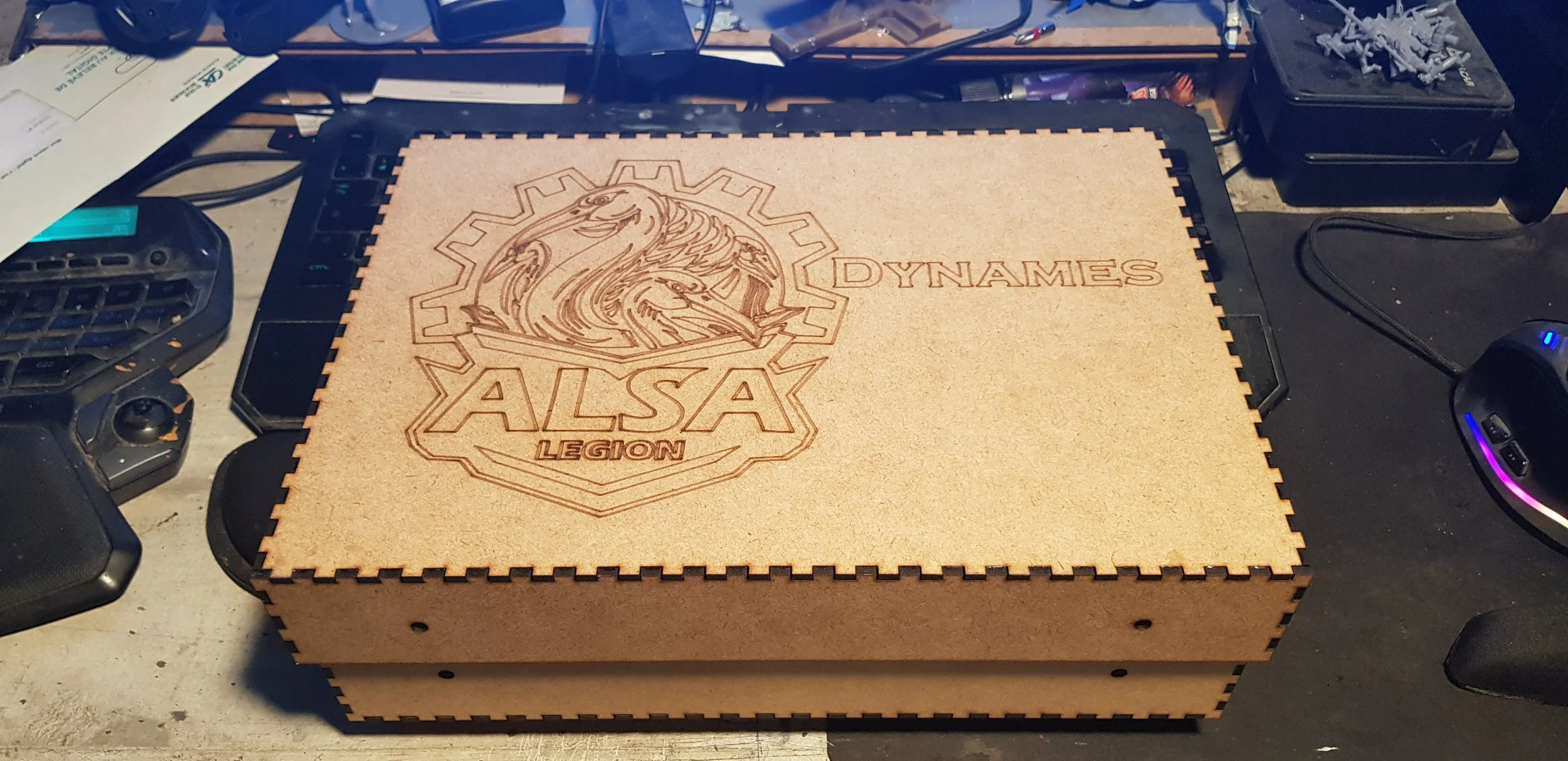 Une boîte en bois gravée avec le logo ALSA LEGION, comprenant un dragon et le texte 'DYNAMES'.