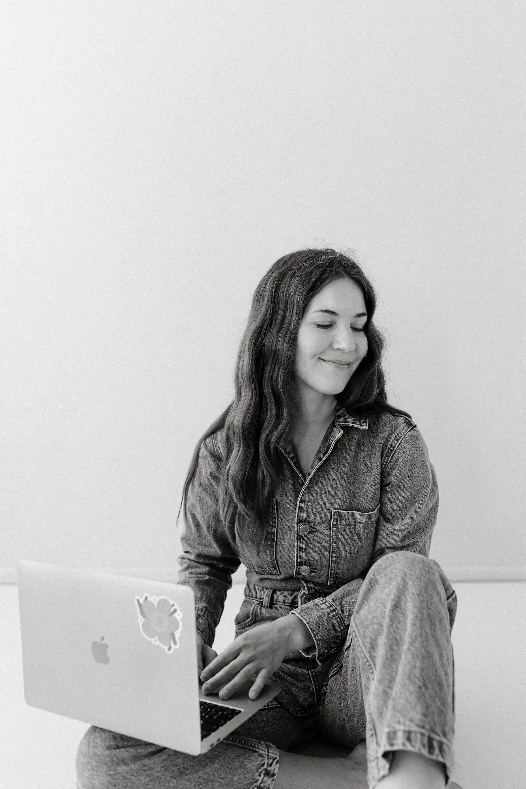 Verkkosivutekijä istuu lattialla kannettavan tietokoneen kanssa ja suunnittelee verkkosivuja.