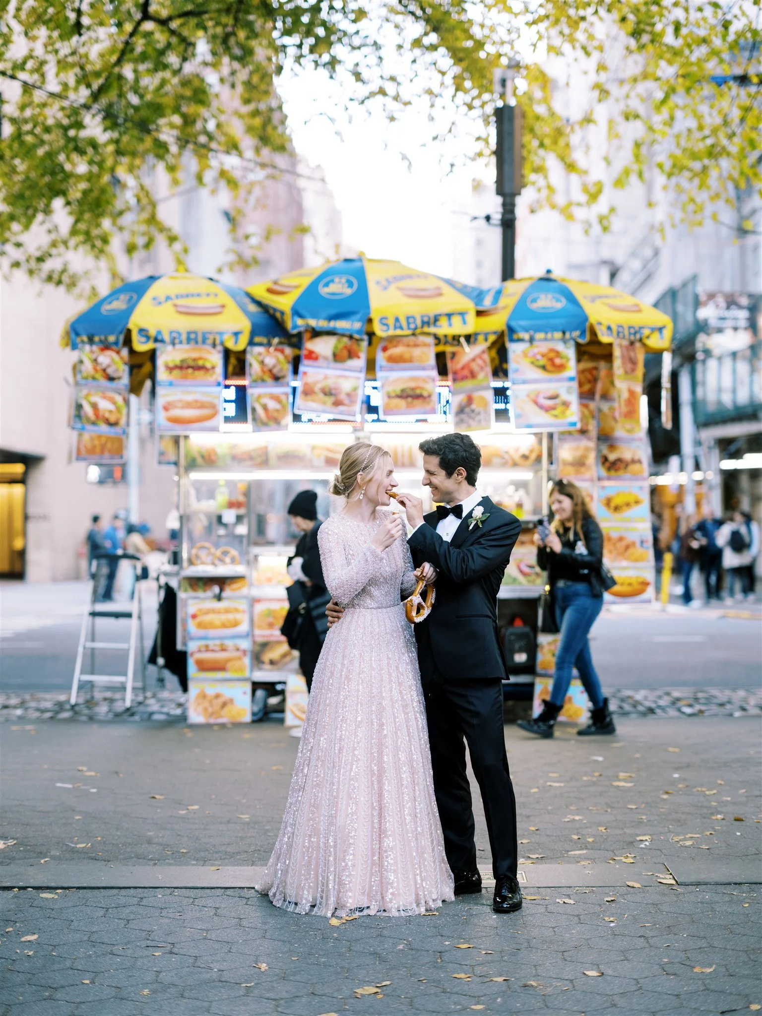 bride & groom sharing a pretzel outside the plaza hotel.  central park wedding, nyc.
