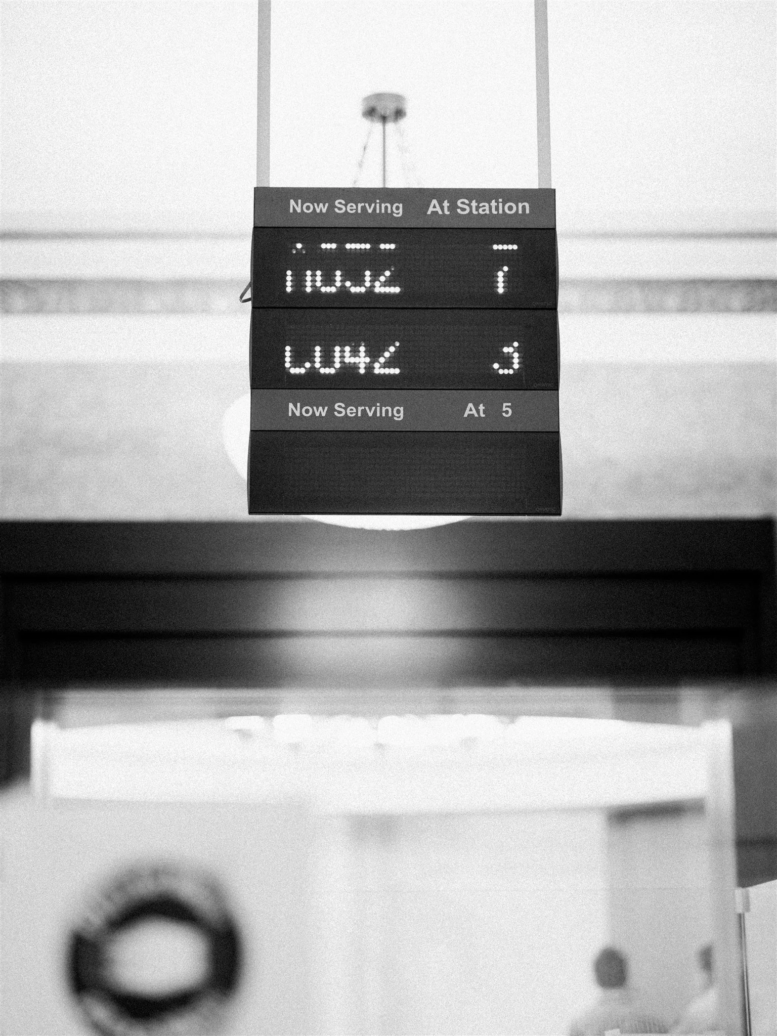 Electronic 'Now Serving' board glows inside the licensing office. editorial wedding photographer new york city.