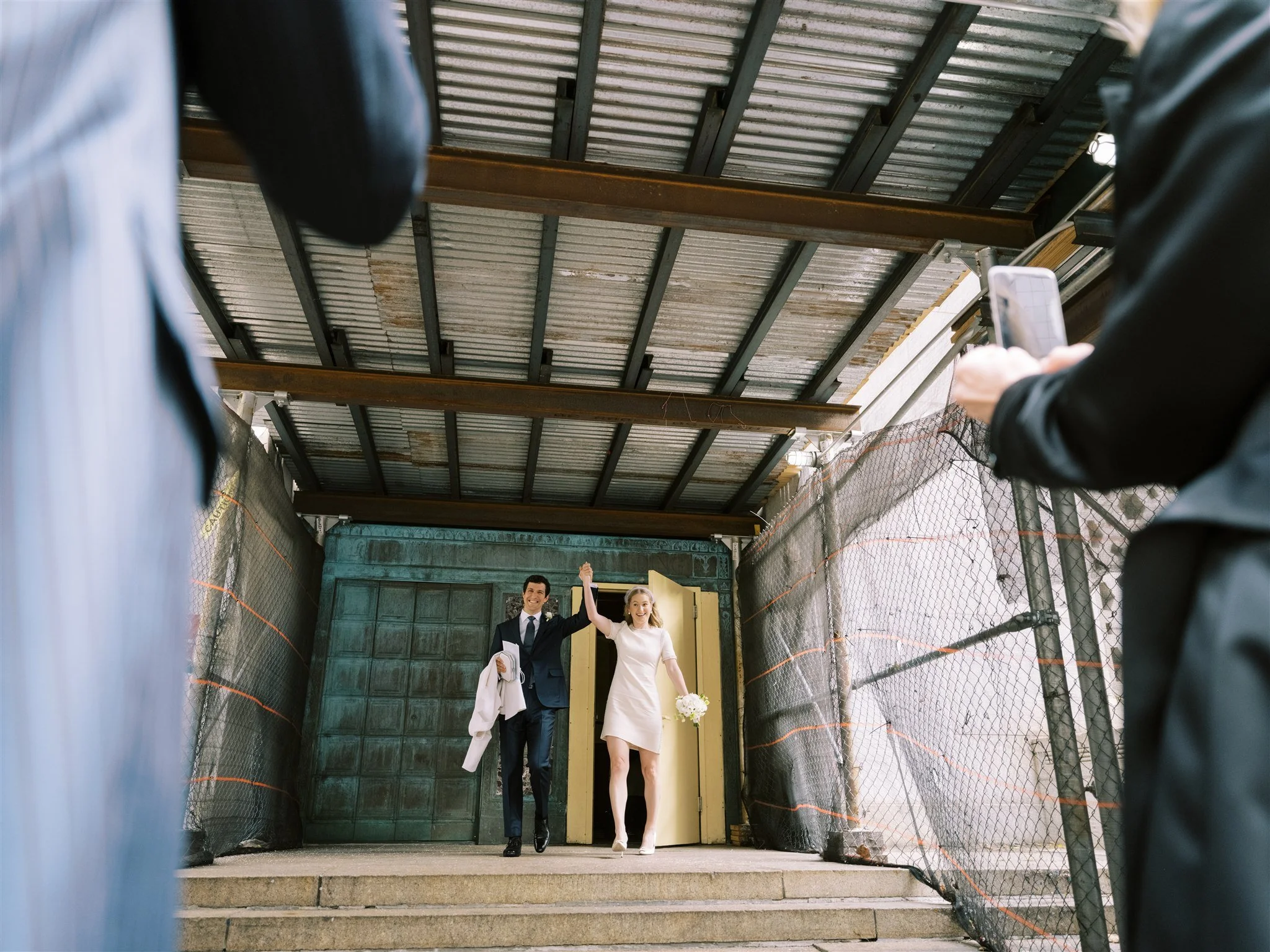 The newlyweds step out of the courthouse doors hand in hand. new york city luxury wedding photographer.