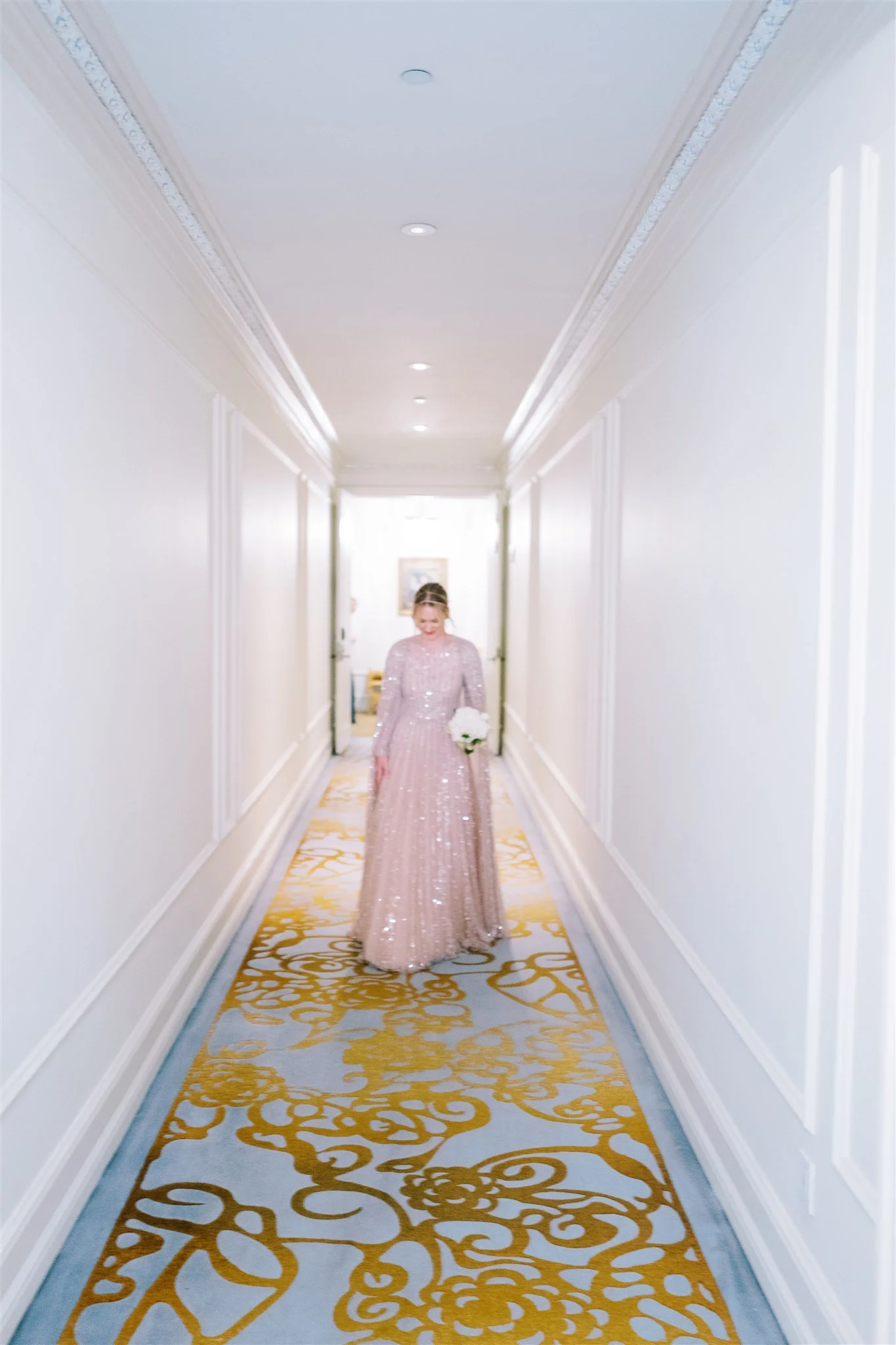 Bride walks down a grand hallway in a sequined gown. new york city luxury wedding photographer.