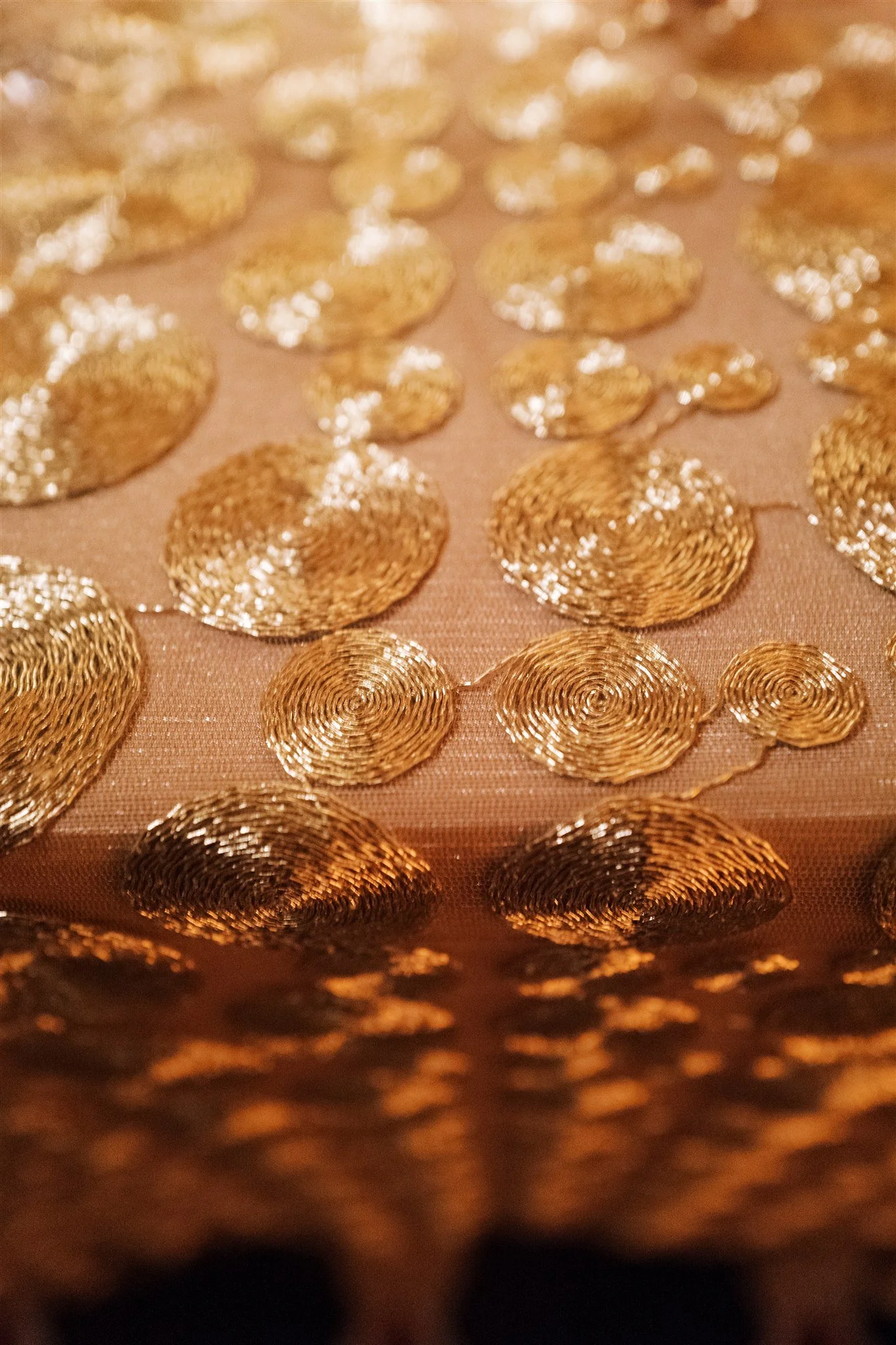 Close-up of gold embroidered tablecloth shimmering in reception light. editorial nyc wedding photography.