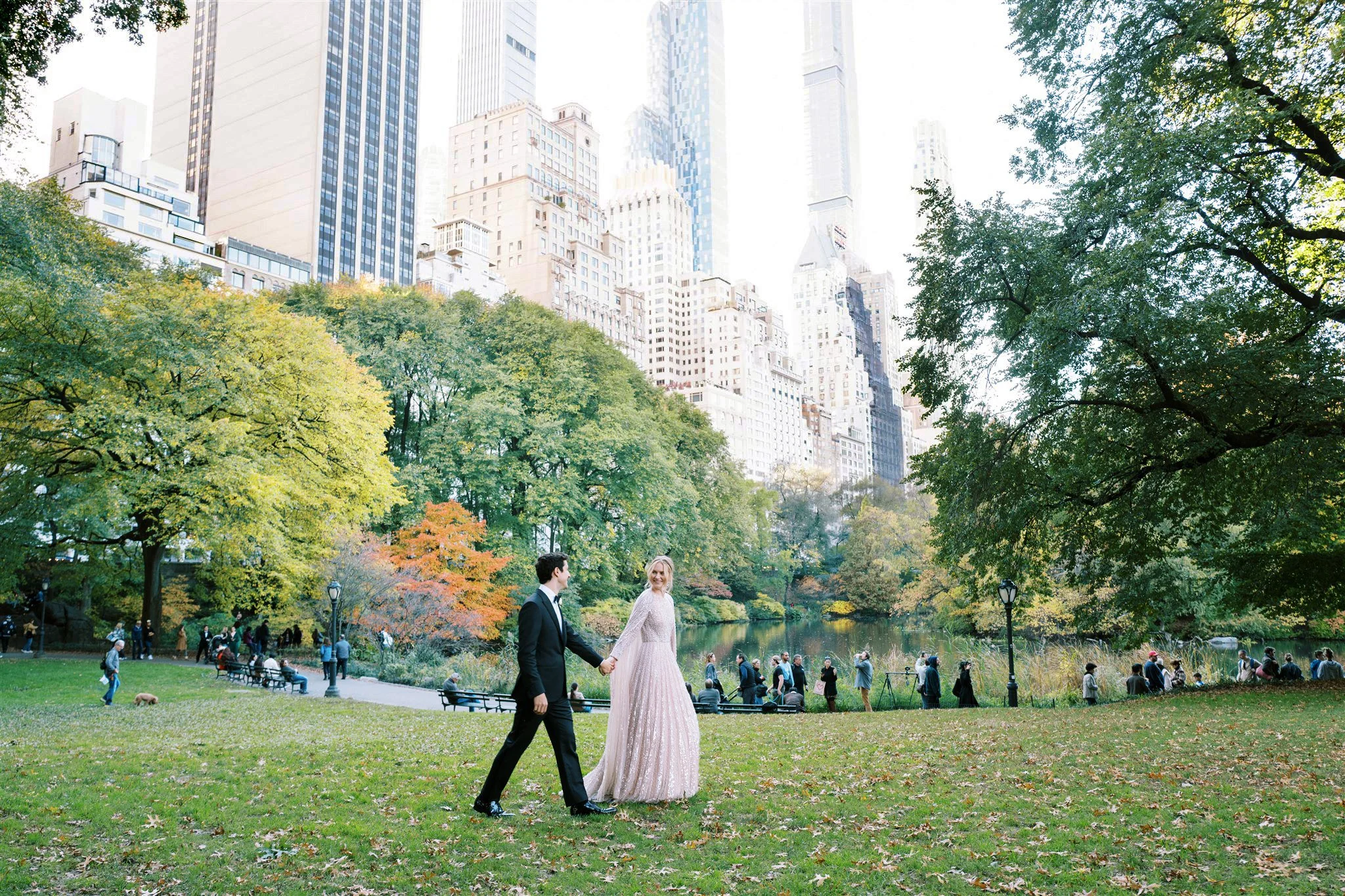 The couple walks through Central Park with the skyline in view. new york city luxury wedding photographer.