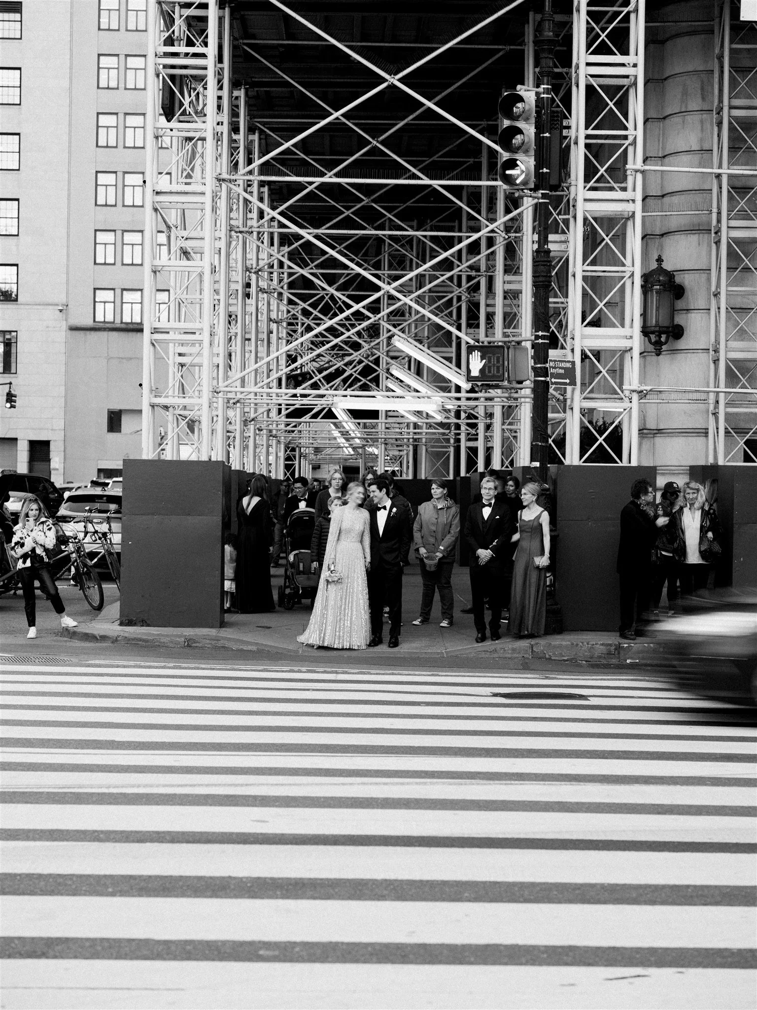 Wedding party gathers under scaffolding at a busy crosswalk. luxury wedding planner michelle rago nyc.