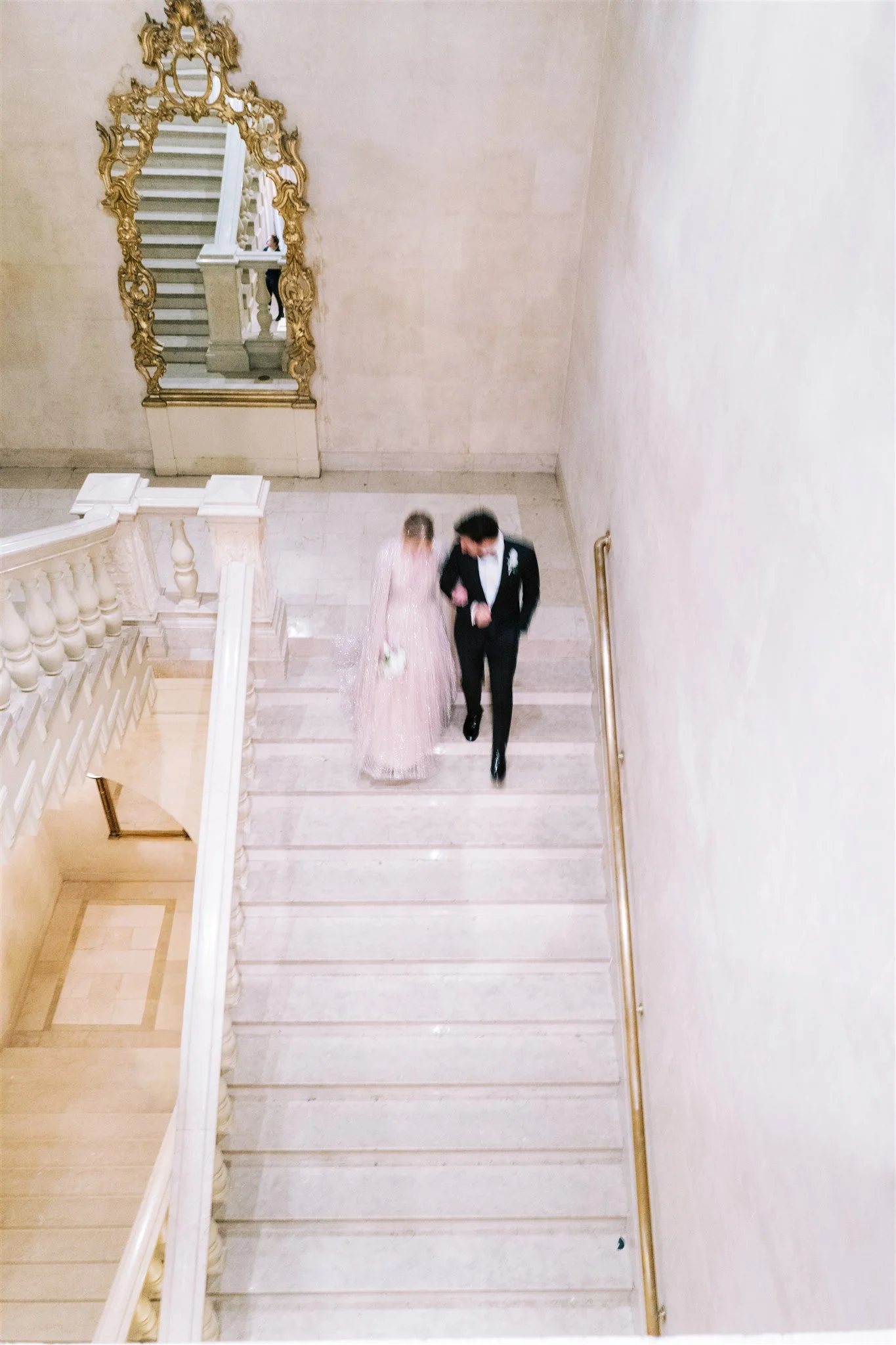 Motion blur as the couple descends the marble staircase. new york city luxury wedding photographer.