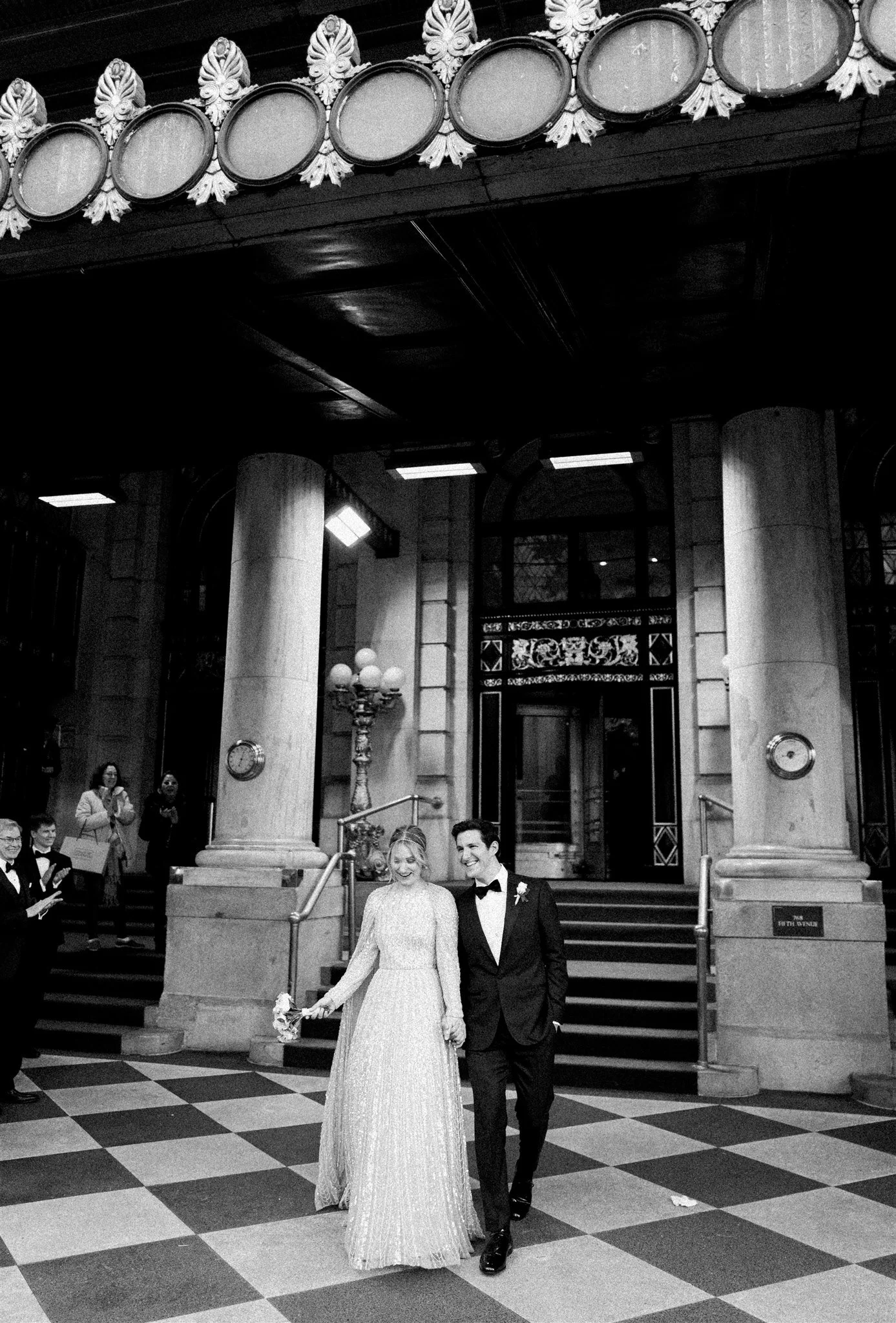 The couple exits beneath The Plaza marquee to cheers. plaza hotel wedding new york city.
