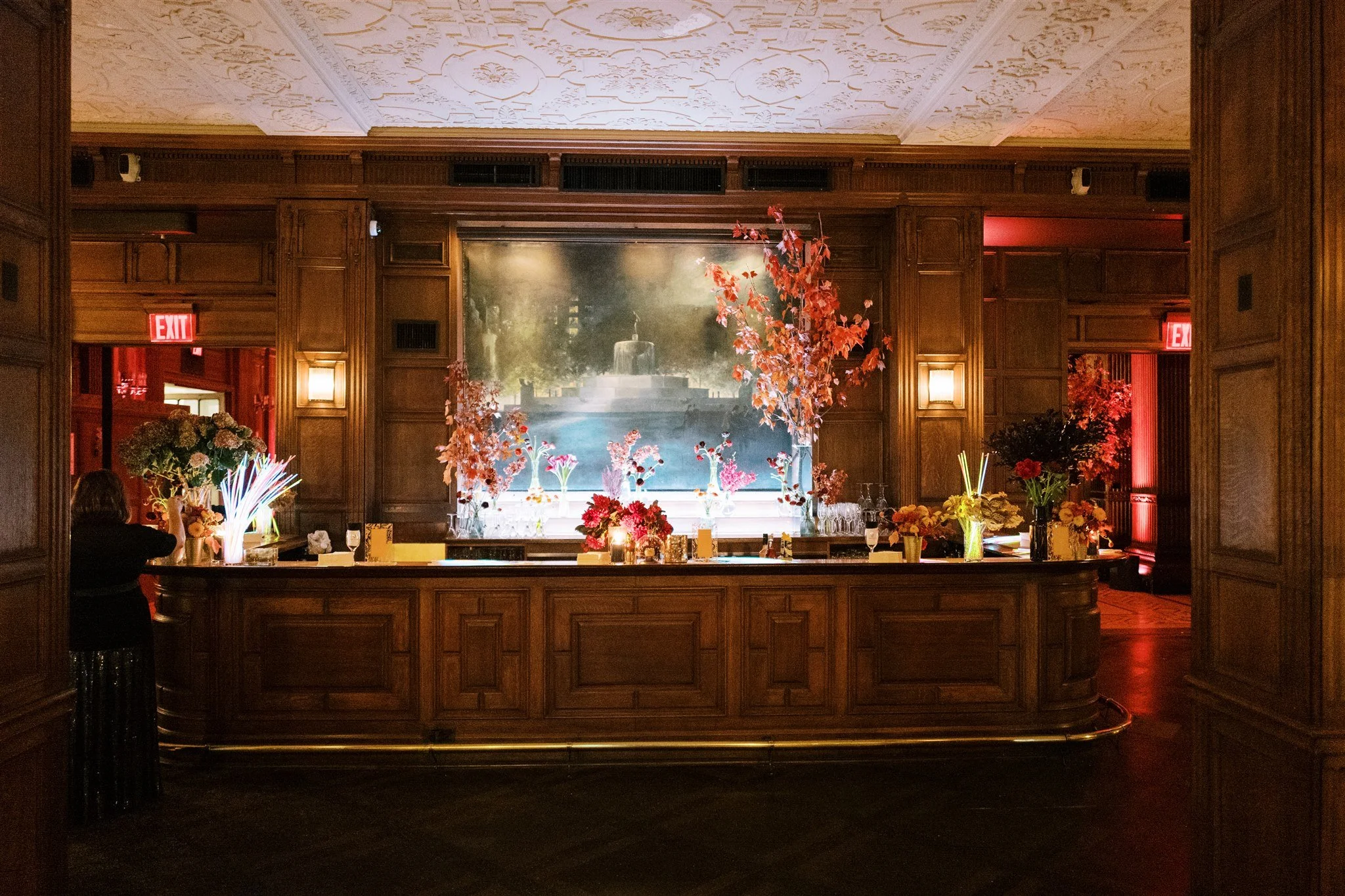 Ornate wood-paneled bar decorated with vibrant floral arrangements and candlelight at a New York luxury wedding. new york city luxury wedding photographer.