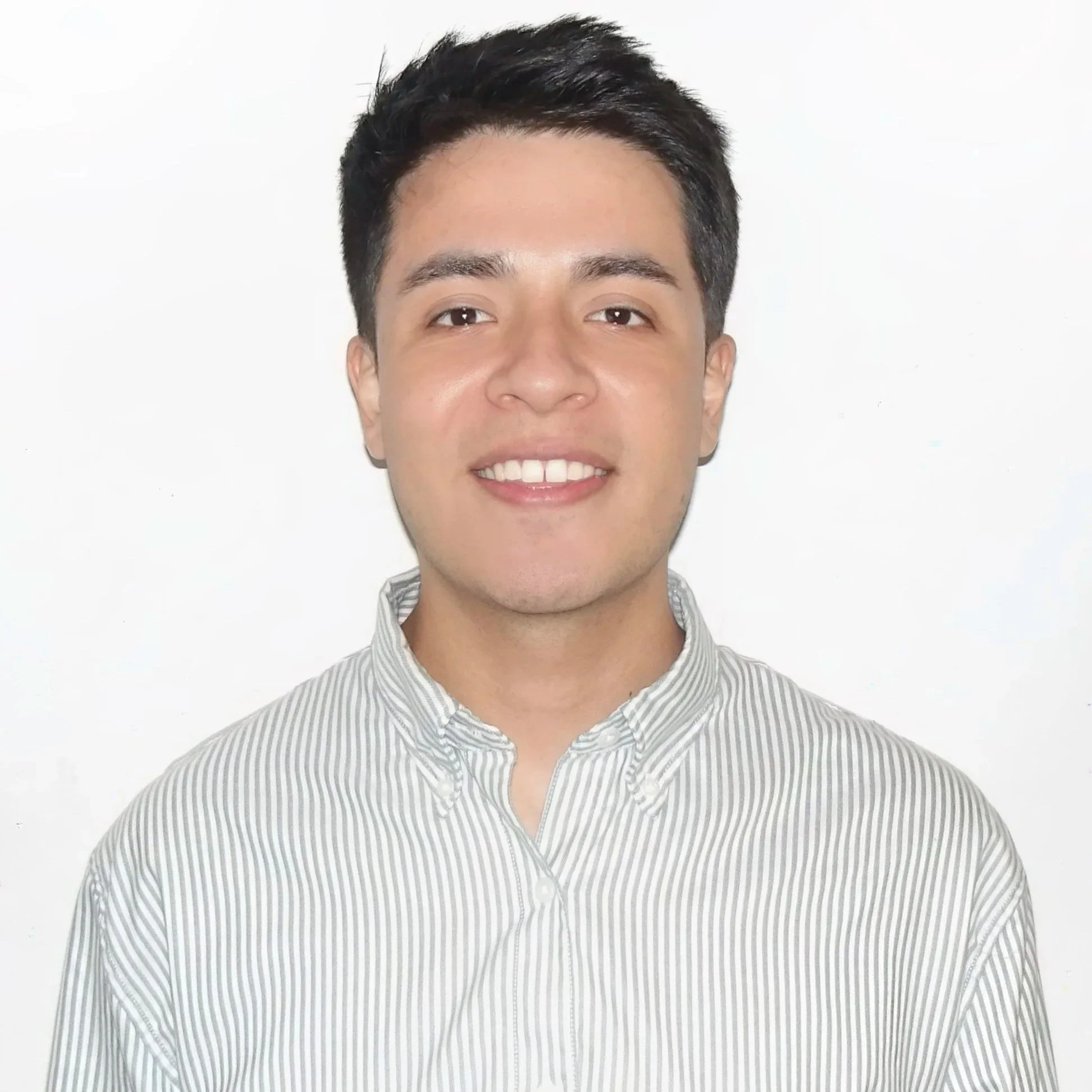 Portrait of a young man with dark hair smiling against a plain white background.