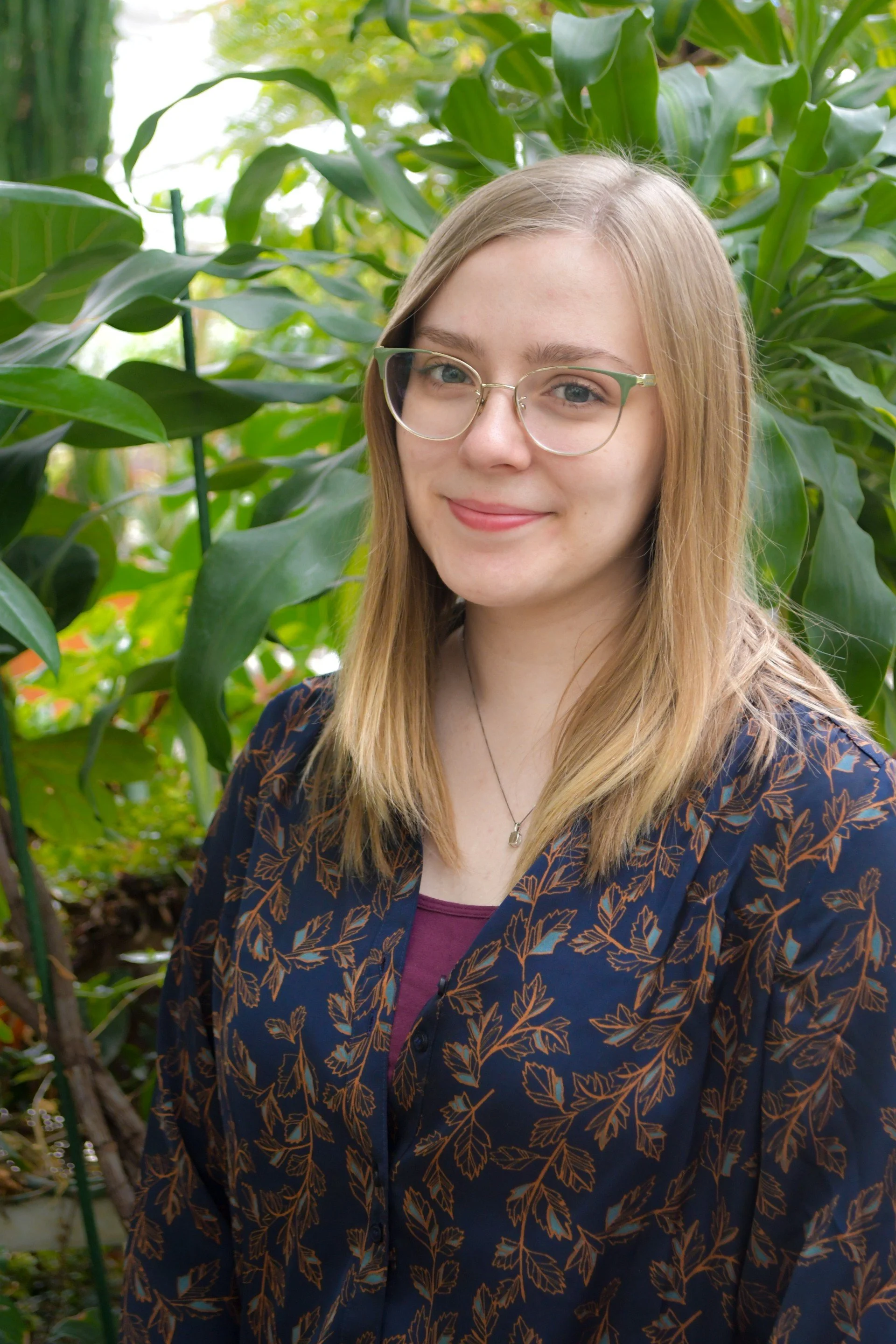 Young woman with glasses standing in front of plants