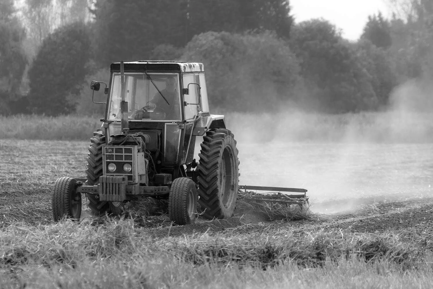 Old classic case tractor working field, black and white photo