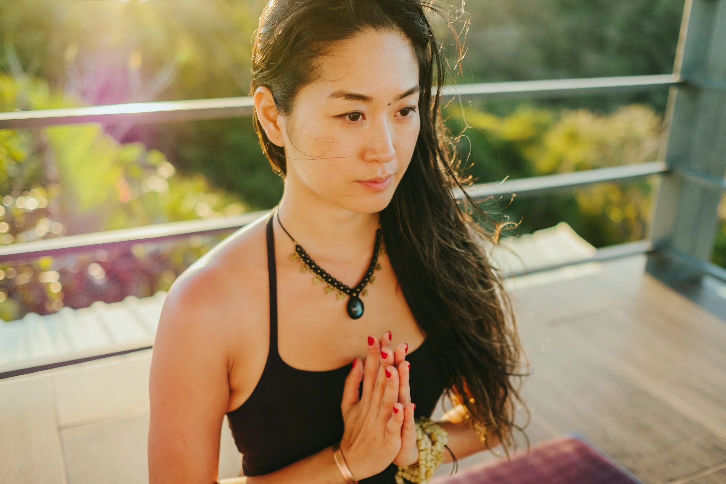 A man smiling and holding a large black and white bulldog puppy in a garden with trees and a wooden fence in the background.