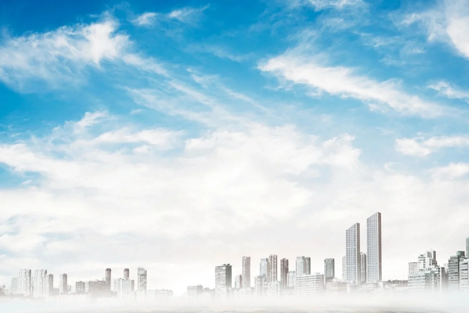 A city skyline with tall buildings under a blue sky with scattered clouds.