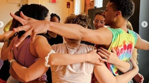 Group embracing and hugging each other in a close circle indoors.