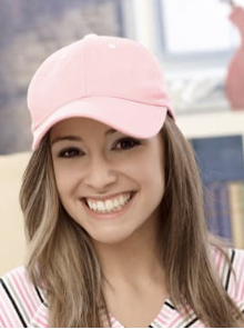 A young woman with long hair, smiling, wearing a pink cap and a striped shirt.