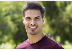 Smile of a young man outdoors with trees in the background