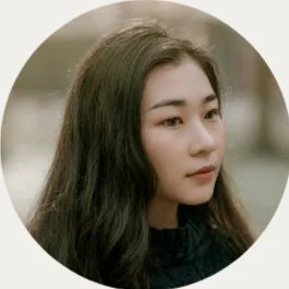 A young Asian woman with long dark hair looking to the right, wearing a black top.