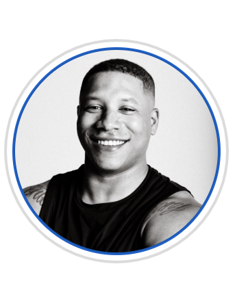 Black and white portrait of a smiling man with short hair, wearing a sleeveless shirt, looking directly at the camera.