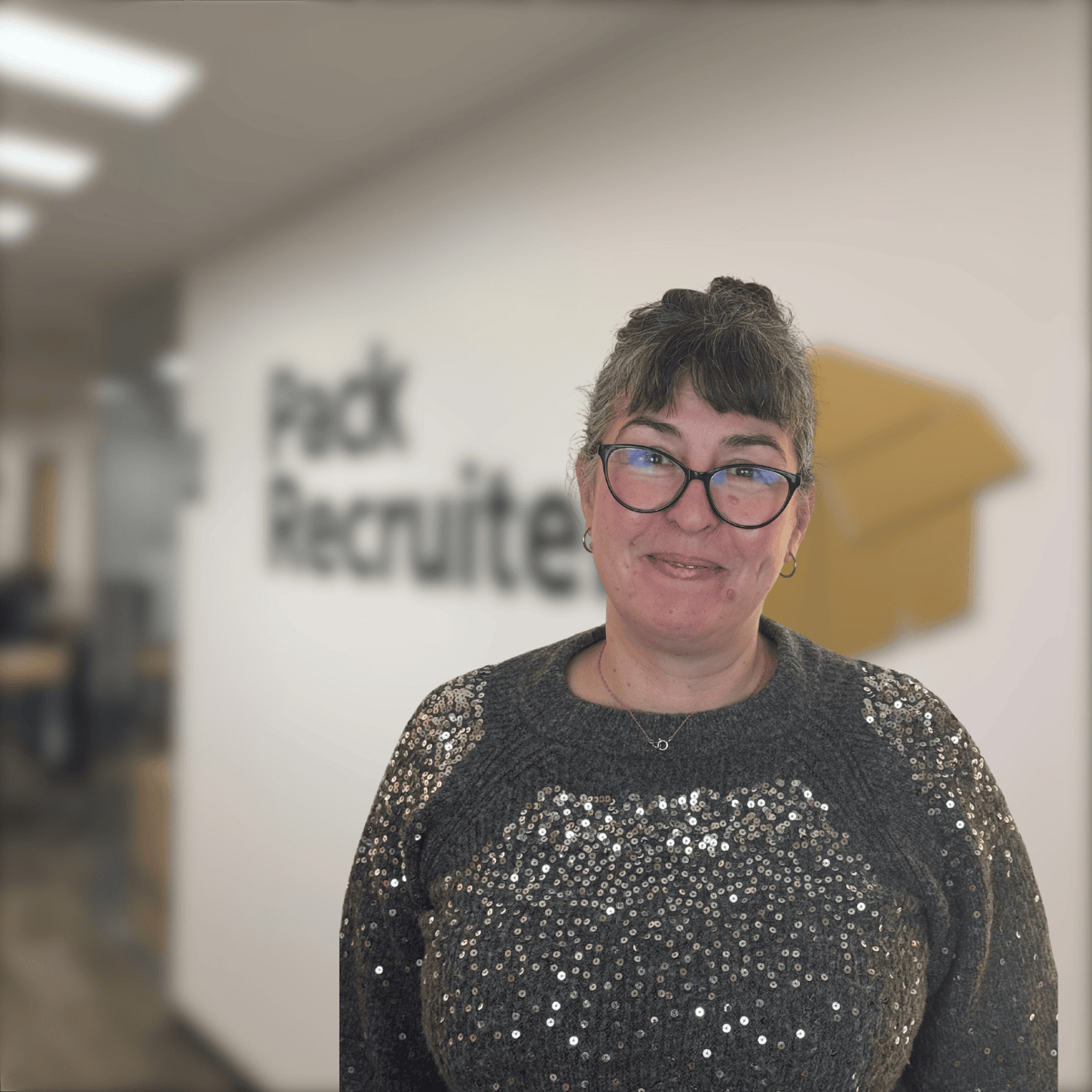 Photo of Clare smiling with Pack Recruiter office in the background