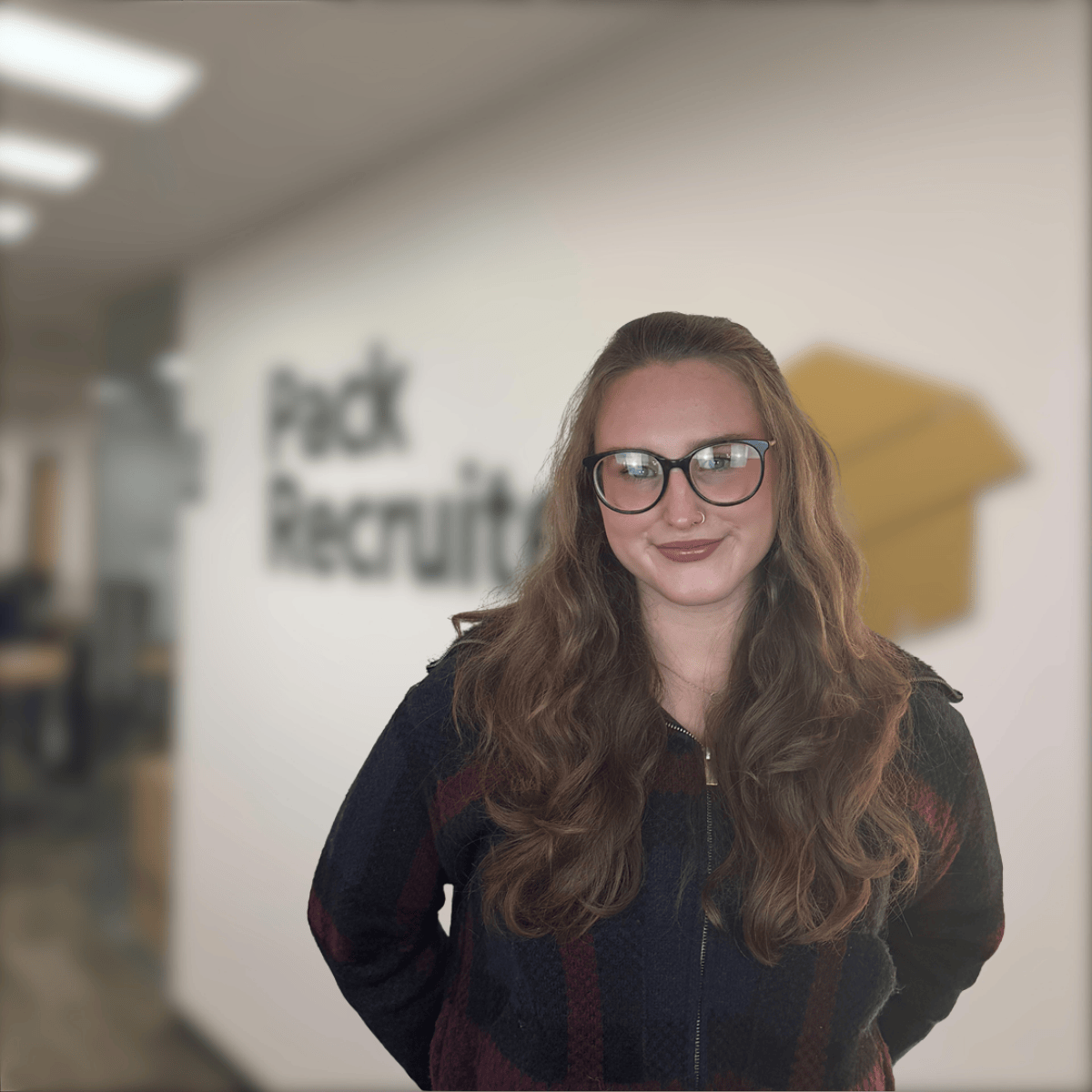 Photo of Lucy smiling with Pack Recruiter office in the background