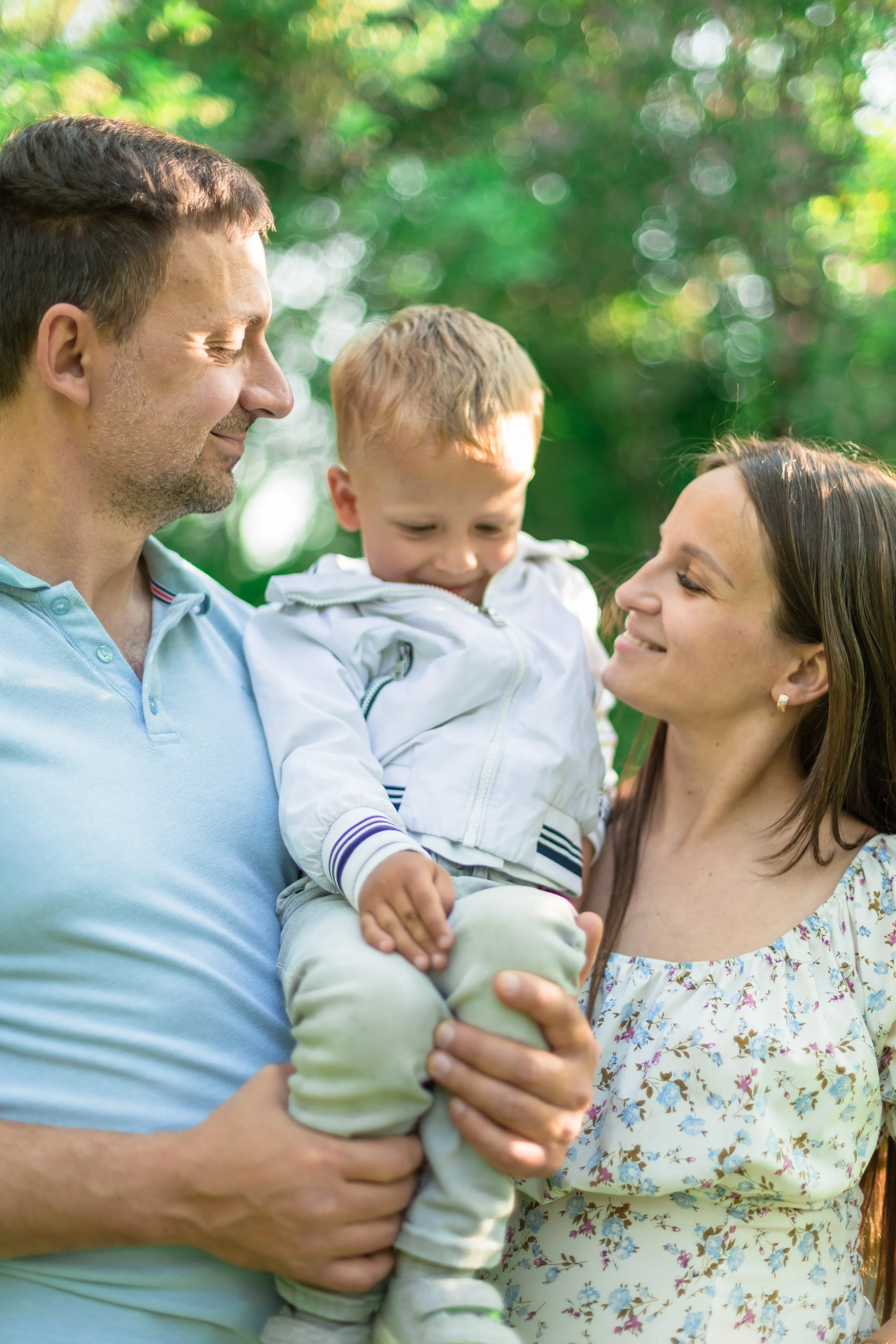 A family of three is smiling with love in Reader Rock Garden in Calgary. 