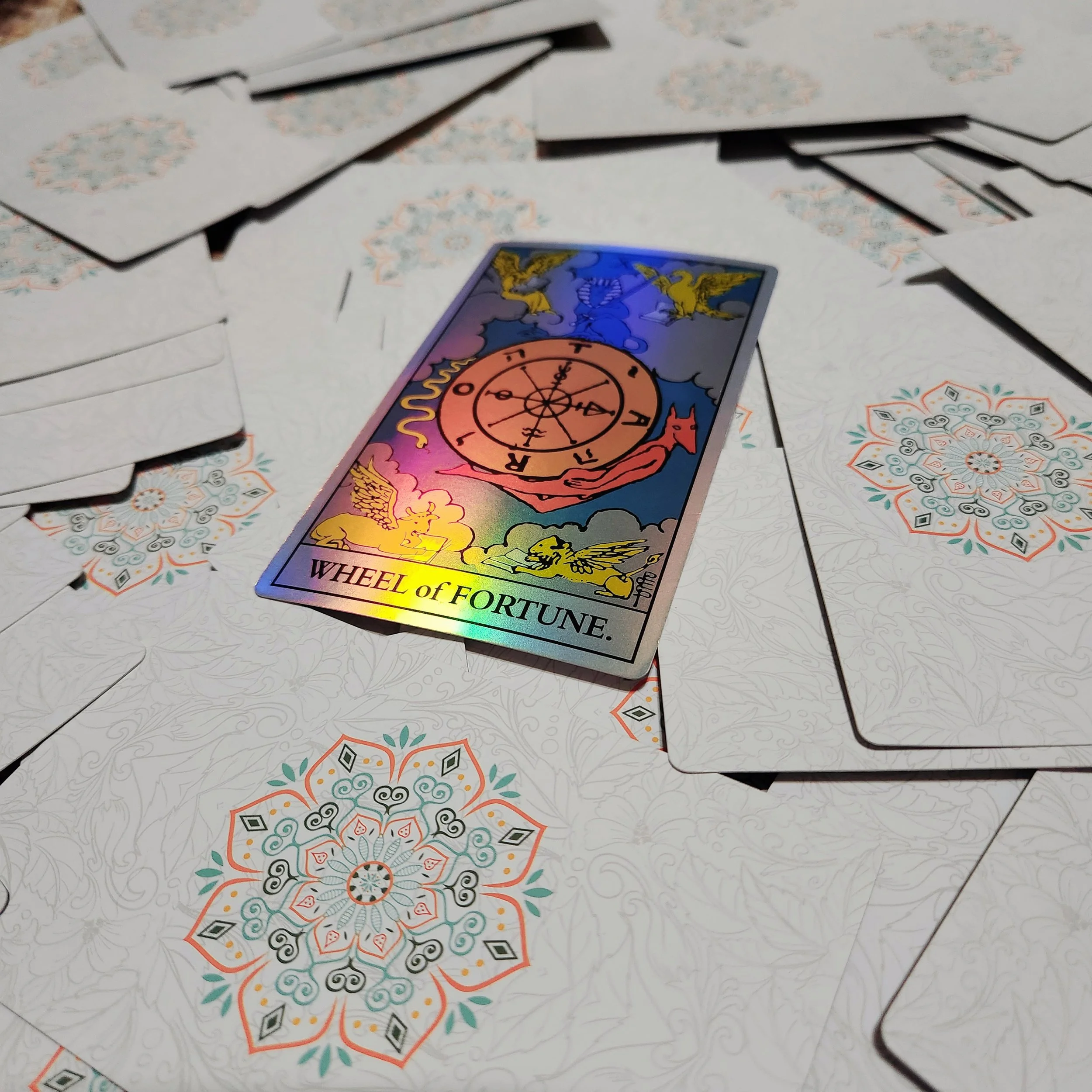 A pile of white cards with a mandala. The center card is The Wheel of Fortune tarot card 