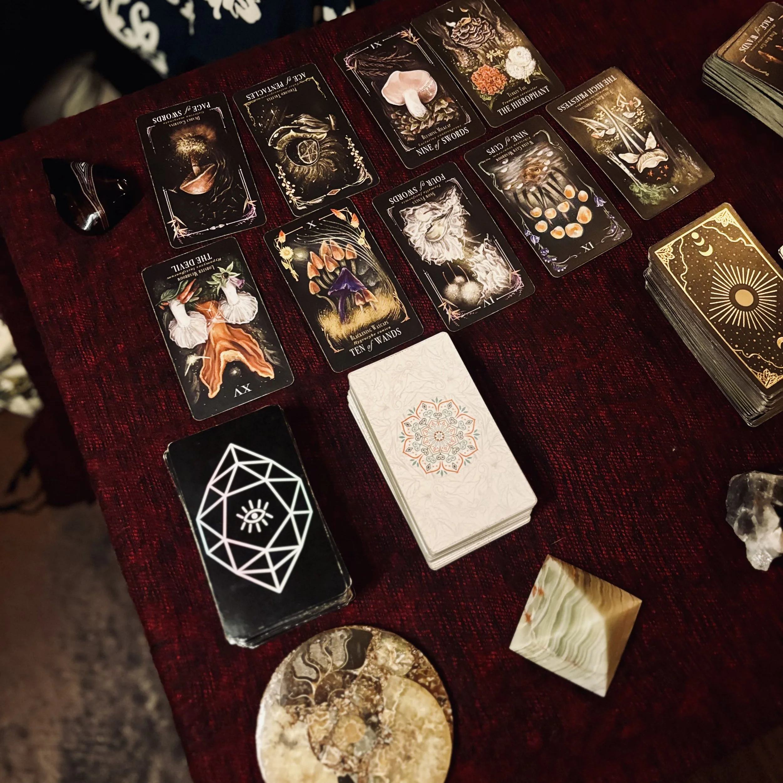 A table with red cloth, covered in tarot cards and crystals