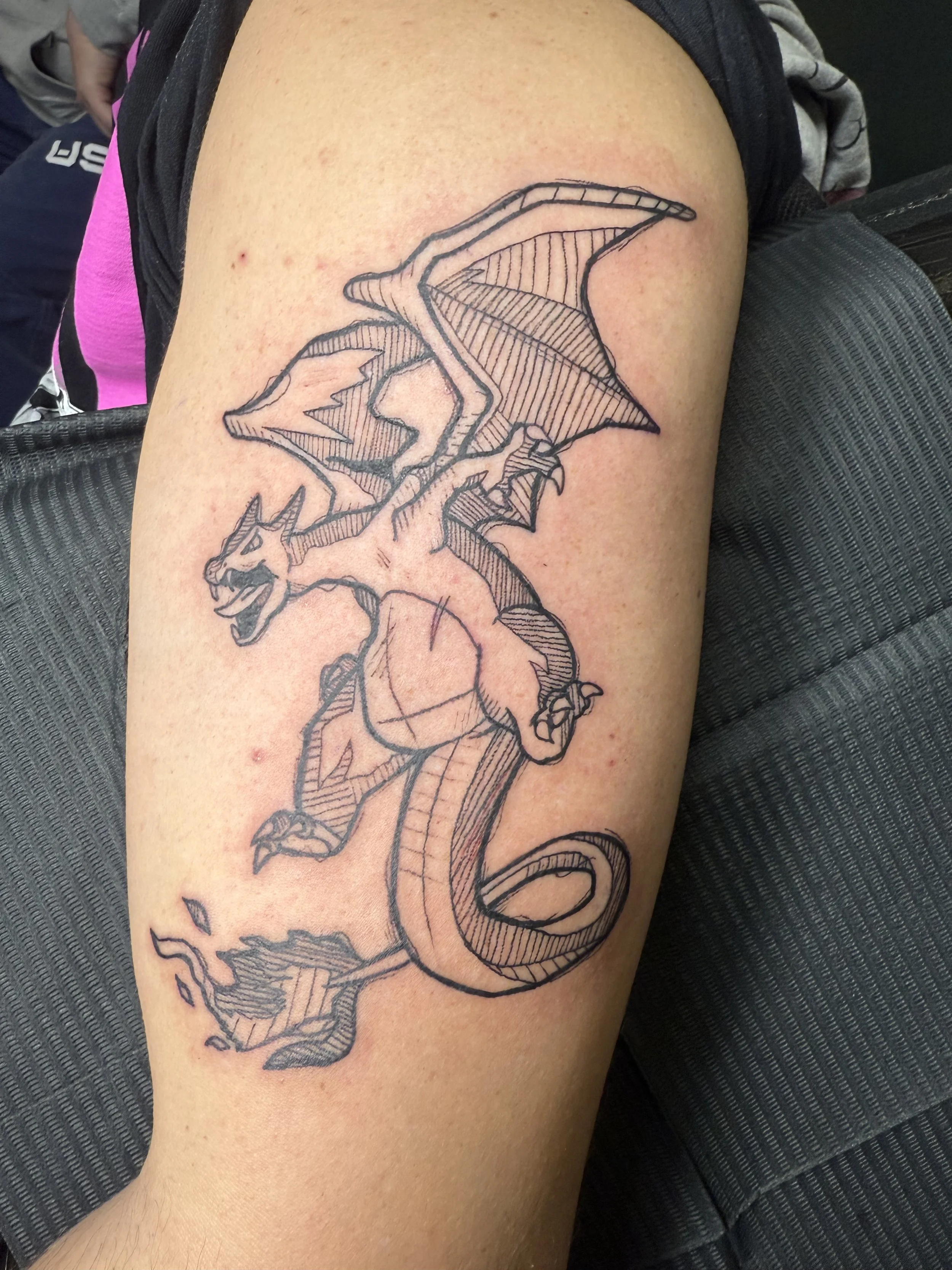 Line drawing of a dragon tattoo on a person's arm.
