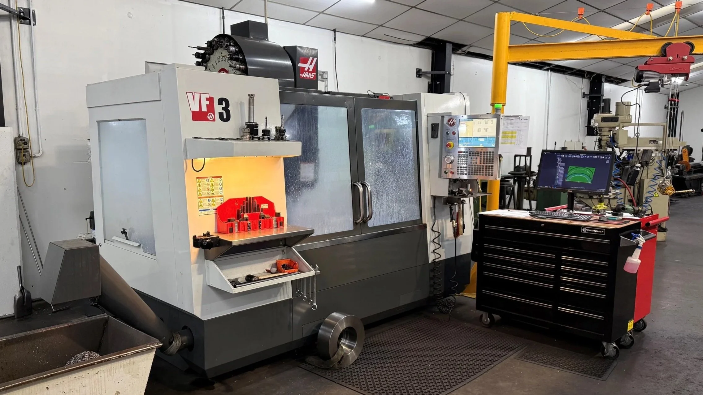 Industrial CNC Verticle Machining Center in a workshop with tools and equipment nearby.