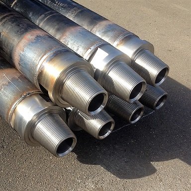 A close-up view of a large number of metallic, threaded mechanical parts arranged in rows.