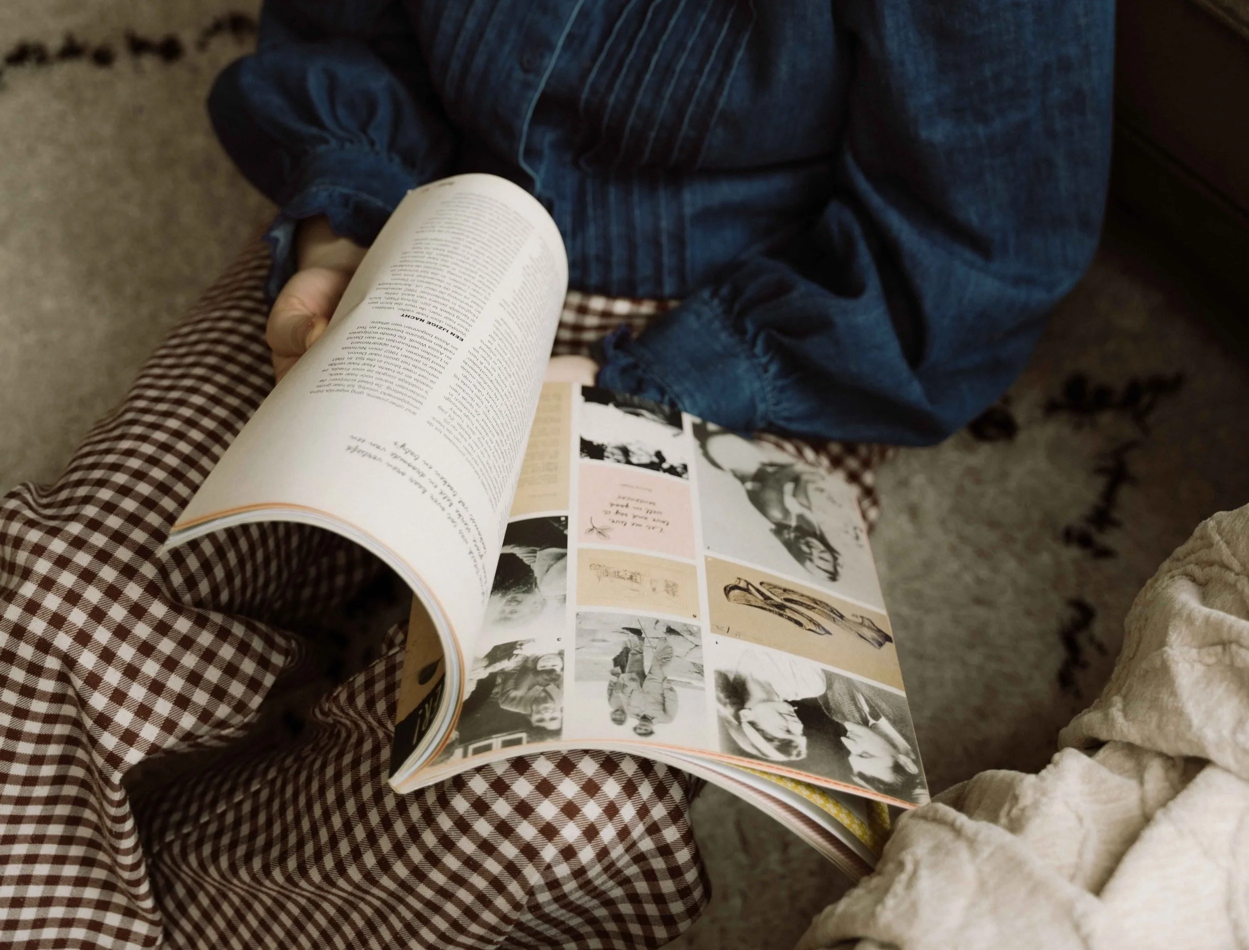 Persoon leest een tijdschrift met zwart-wit en gekleurde foto's in een woonkamer.