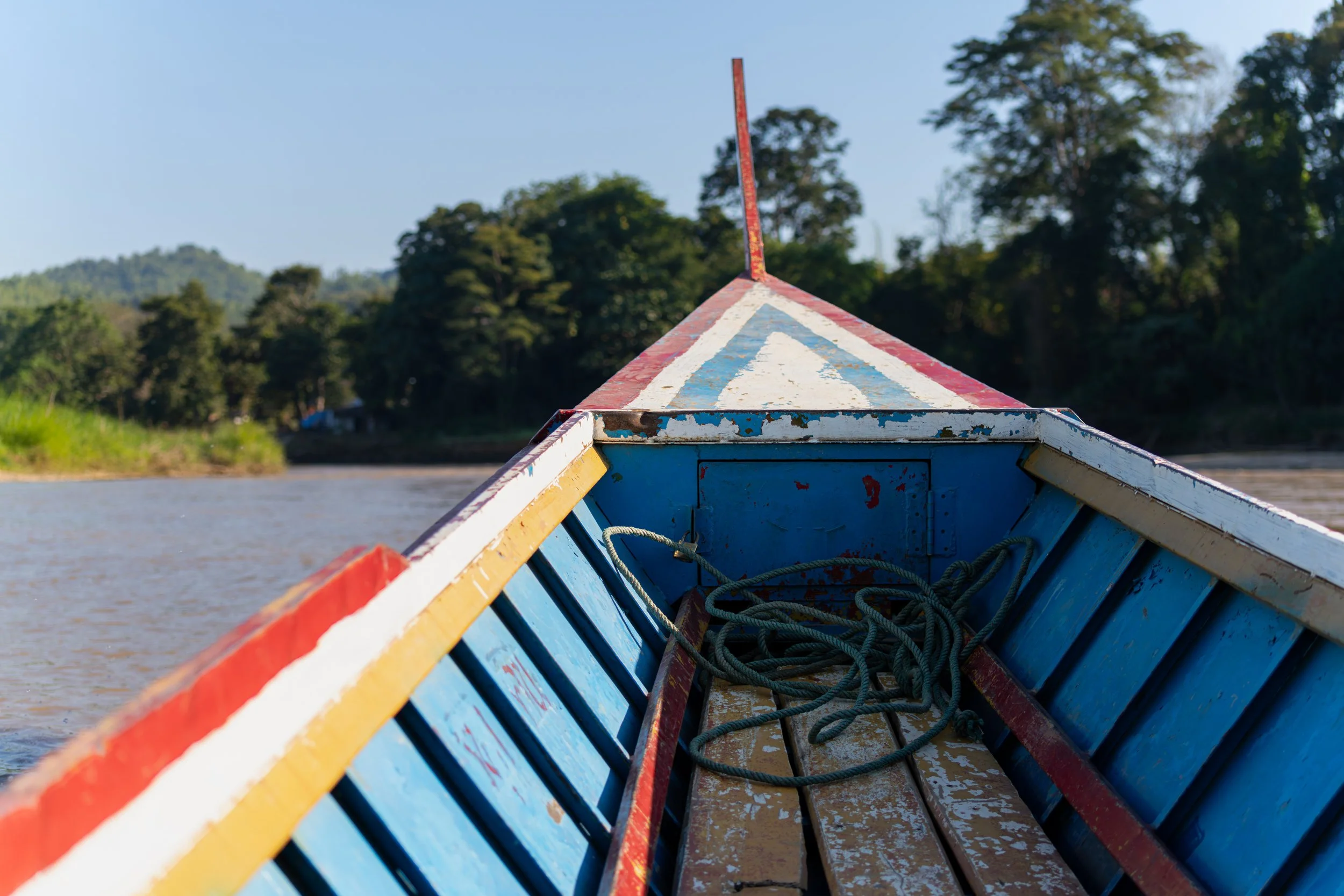 Eine Schnellbootsfahrt auf dem Mae Nam Kok führt rasant durch die grüne Flusslandschaft Nordthailands, vorbei an dichten Uferwäldern und kleinen Siedlungen. Der Fahrtwind, das aufspritzende Wasser und die ruhige Naturkulisse machen dieses Erlebnis be