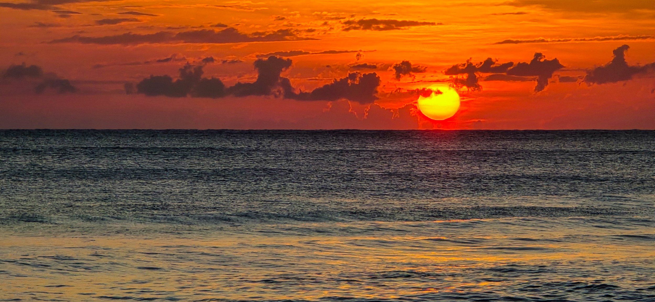 An der Karibikküste von Costa Rica färbt sich der Himmel bei Sonnenuntergang oft intensiv orange und rot und spiegelt die ruhige, tropische Atmosphäre der Region wider.