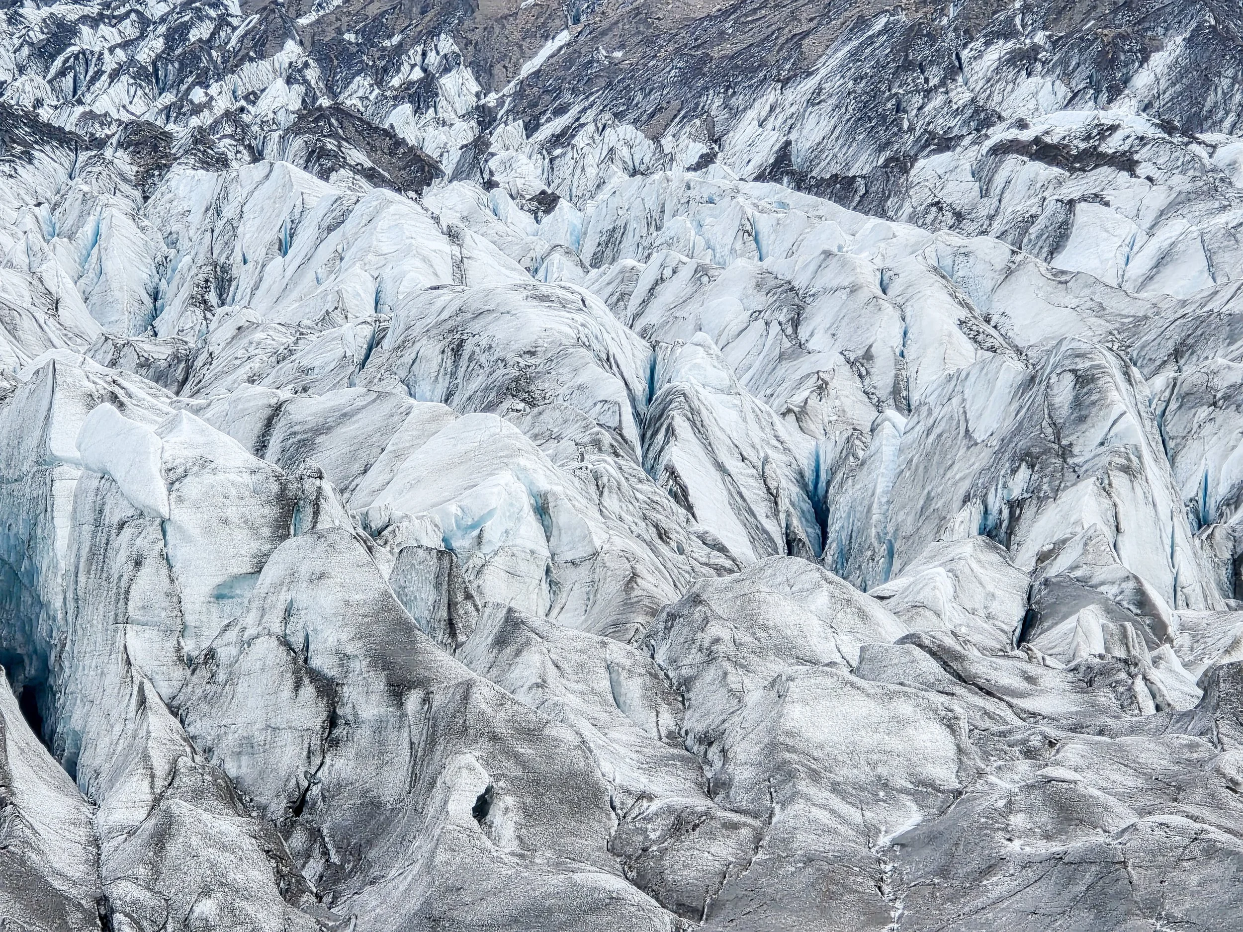Die schwarze oder intensiv blaue Färbung des Eises entsteht durch vulkanische Asche oder durch stark verdichtetes, altes Gletschereis, das Licht kaum reflektiert.
