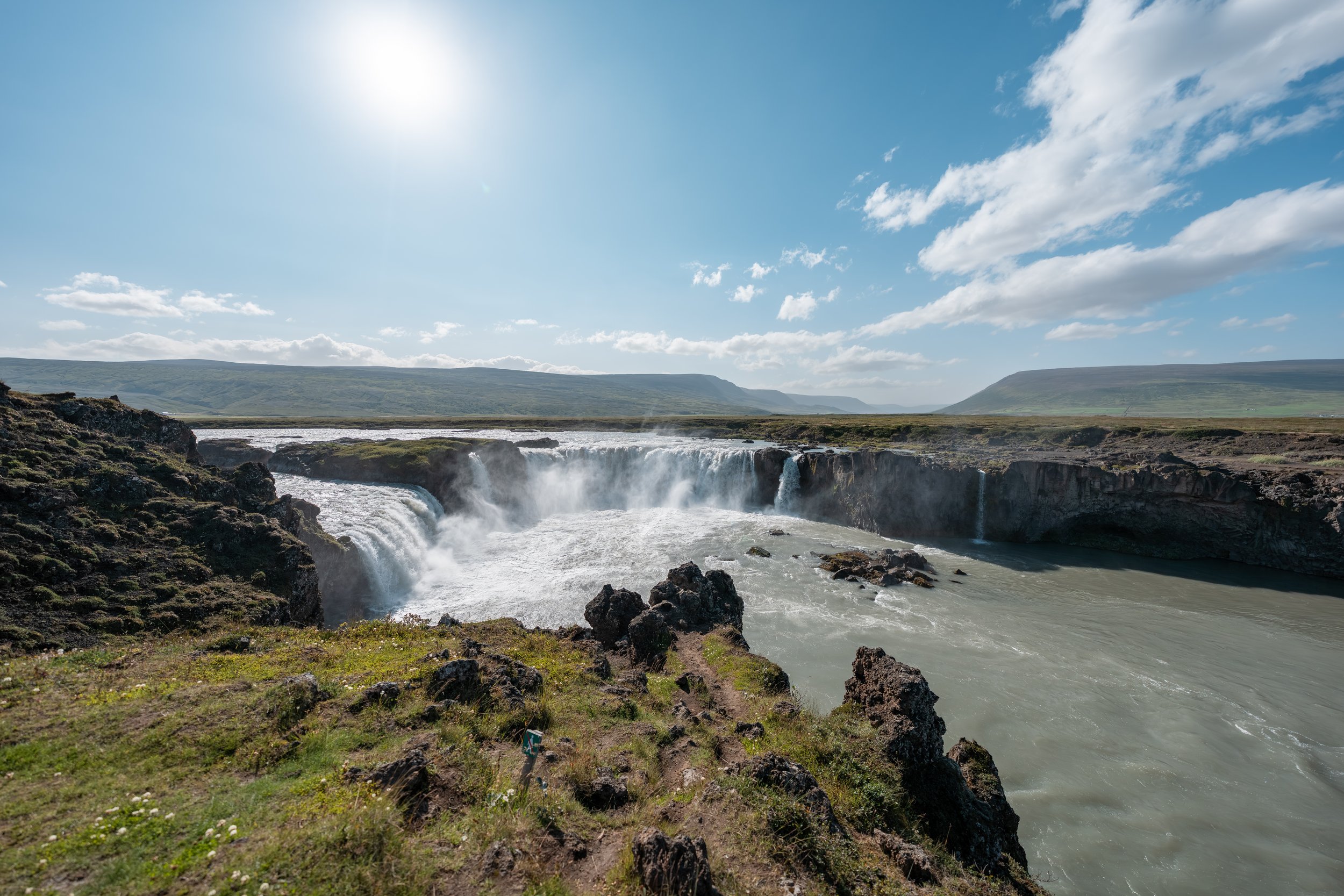 Der Godafoss ist rund 30 Meter breit, etwa 12 Meter hoch und fällt in einer markanten, hufeisenförmigen Kaskade über dunkle Basaltfelsen.
