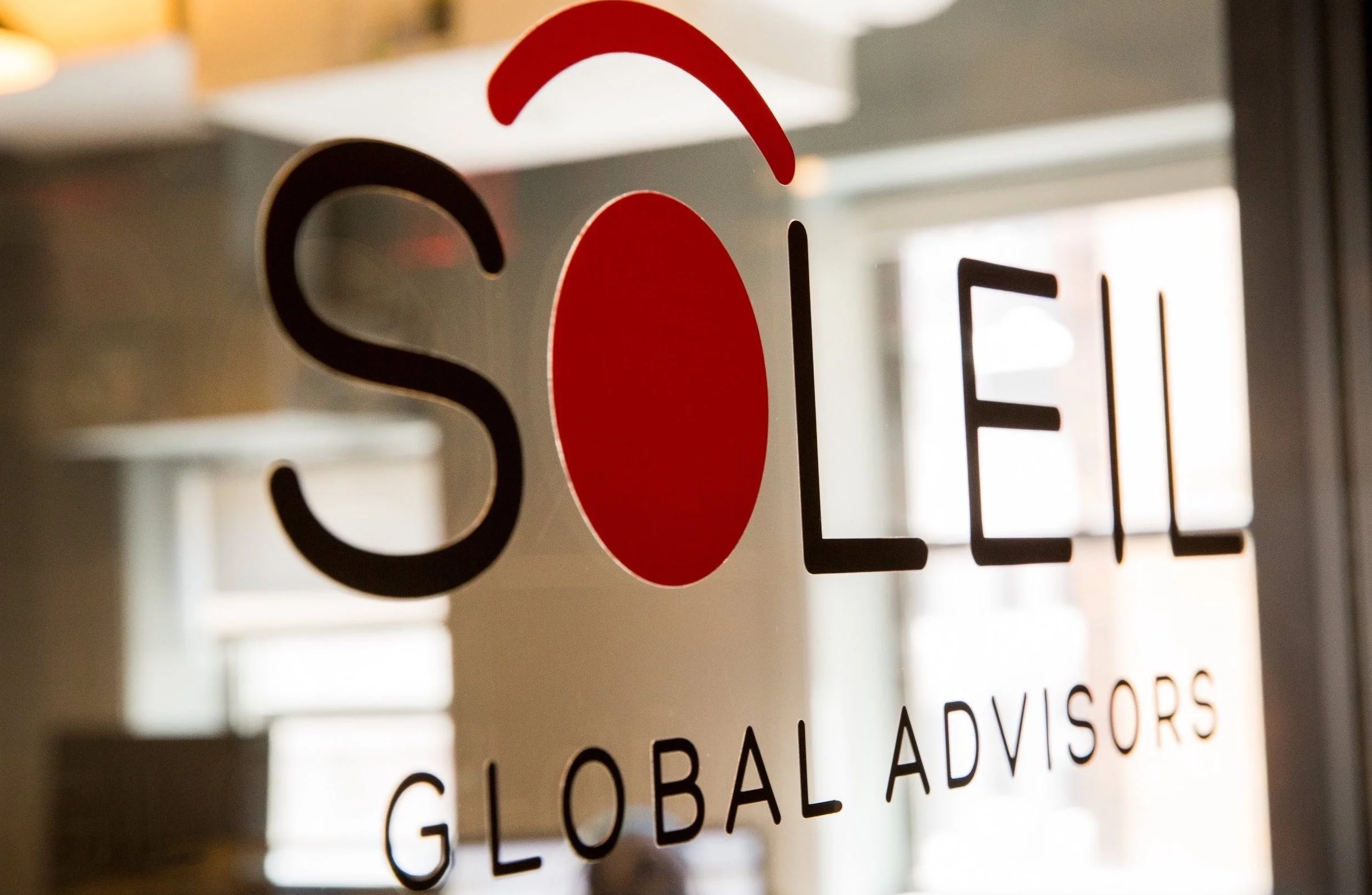 Glass door with 'SOLL' logo and 'Global Advisors' written below, reflecting indoor setting.
