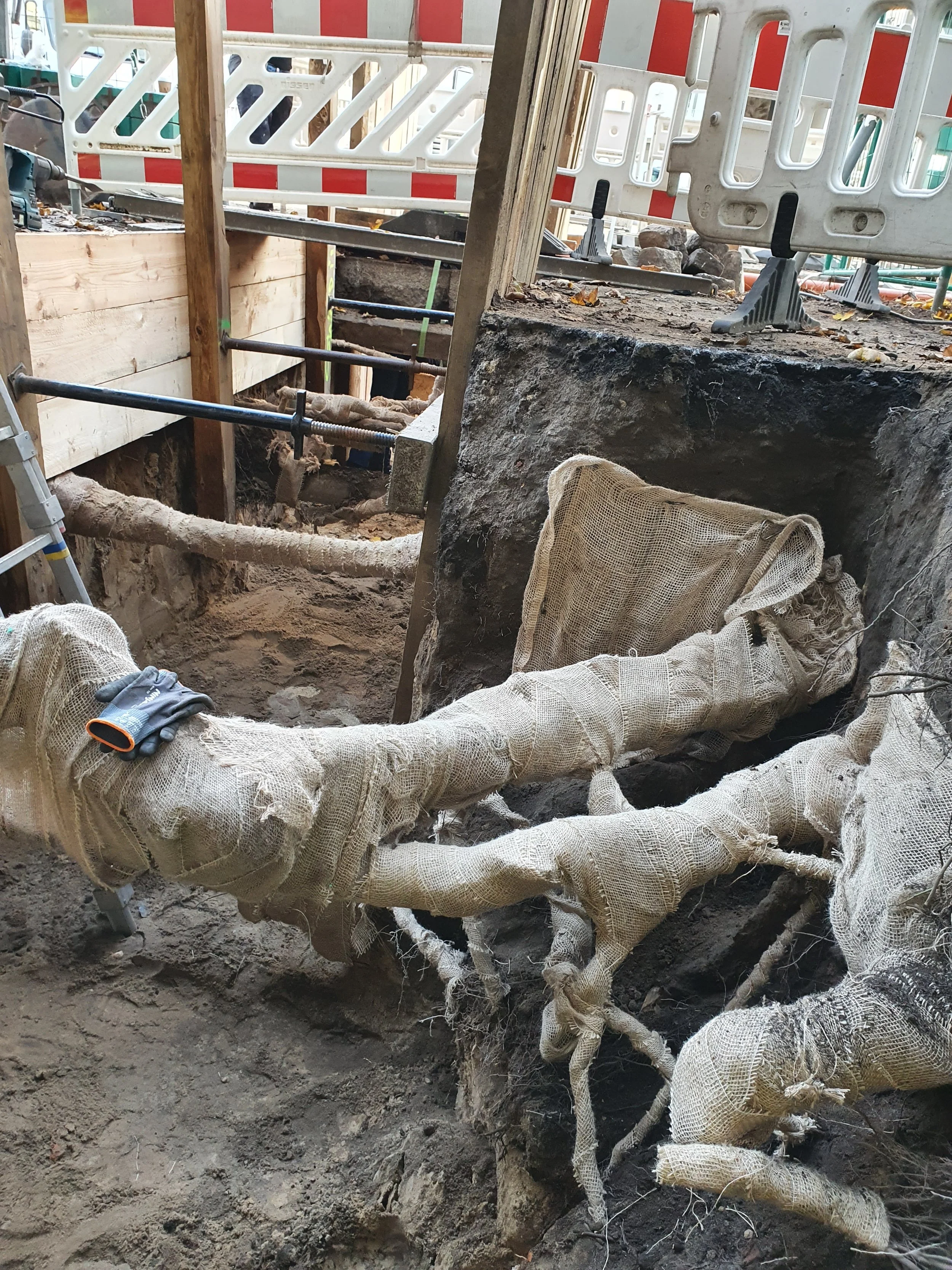 Bauarbeiten mit eingeklemmten Rohrleitungen und Schutzvorrichtungen auf einer Baustelle.