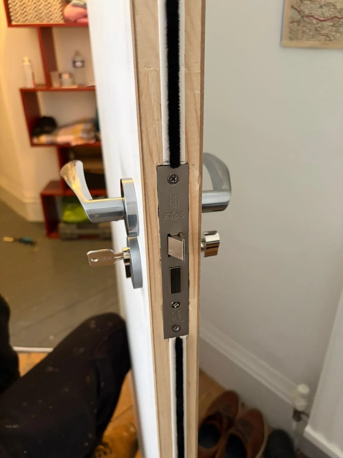 Close-up of a door lock mechanism with a latch and deadbolt, installed in a wooden door.